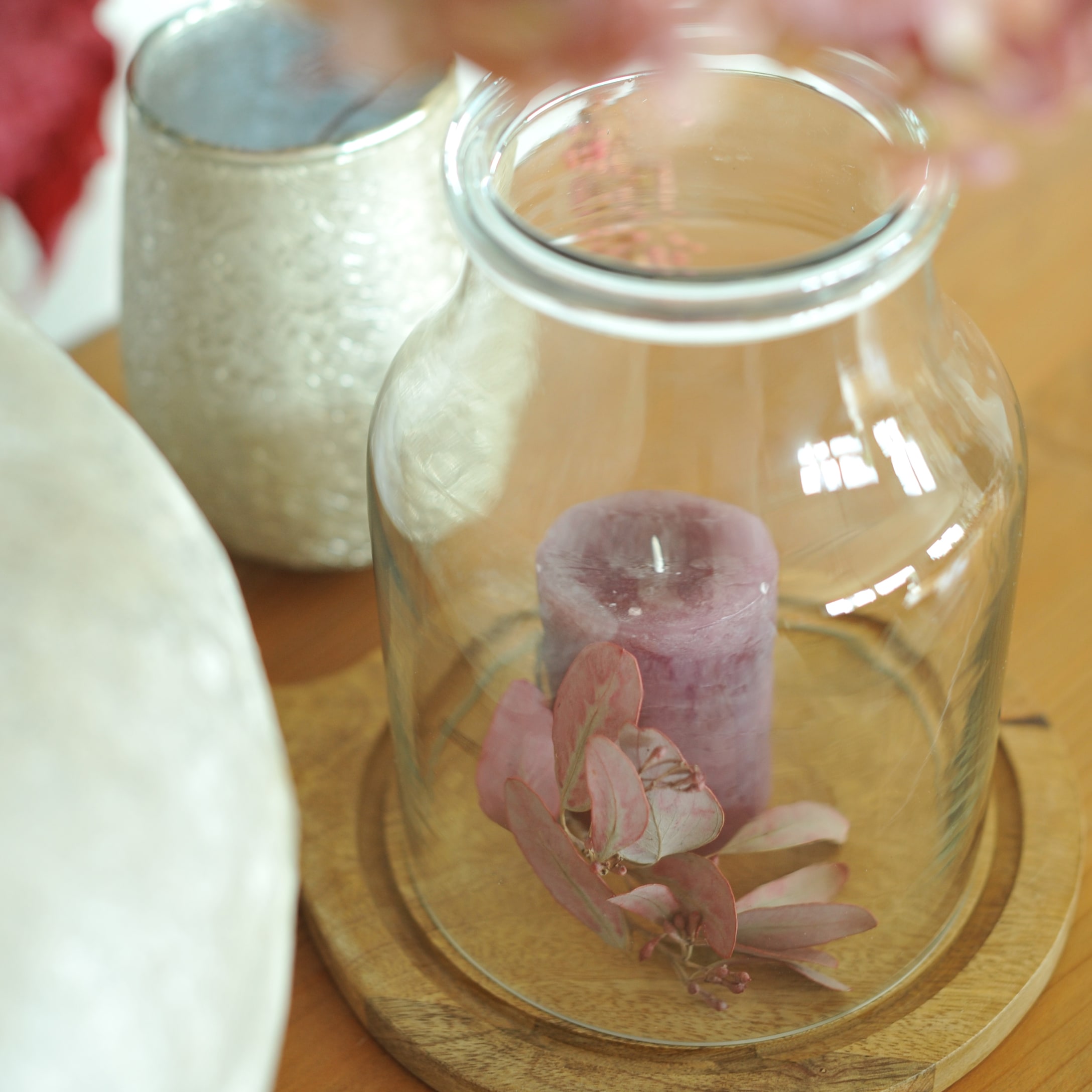 Campana di vetro su base in legno con candela viola e foglie secche decorative