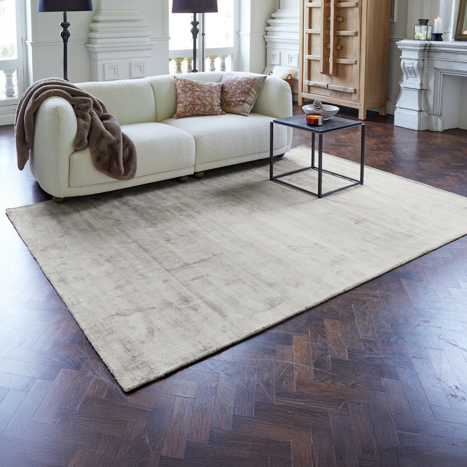Tappeto Mariselle Tappeto beige chiaro su pavimento in legno scuro in soggiorno moderno con divano bianco e tavolino nero
