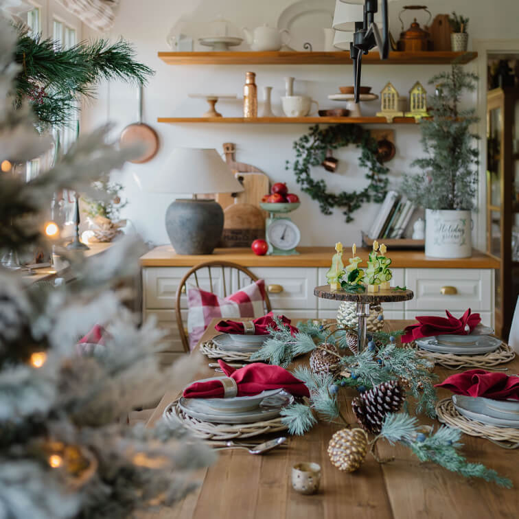 Tavolo in legno decorato per Natale con tovaglioli rossi e decorazioni naturali di pigne e rami
