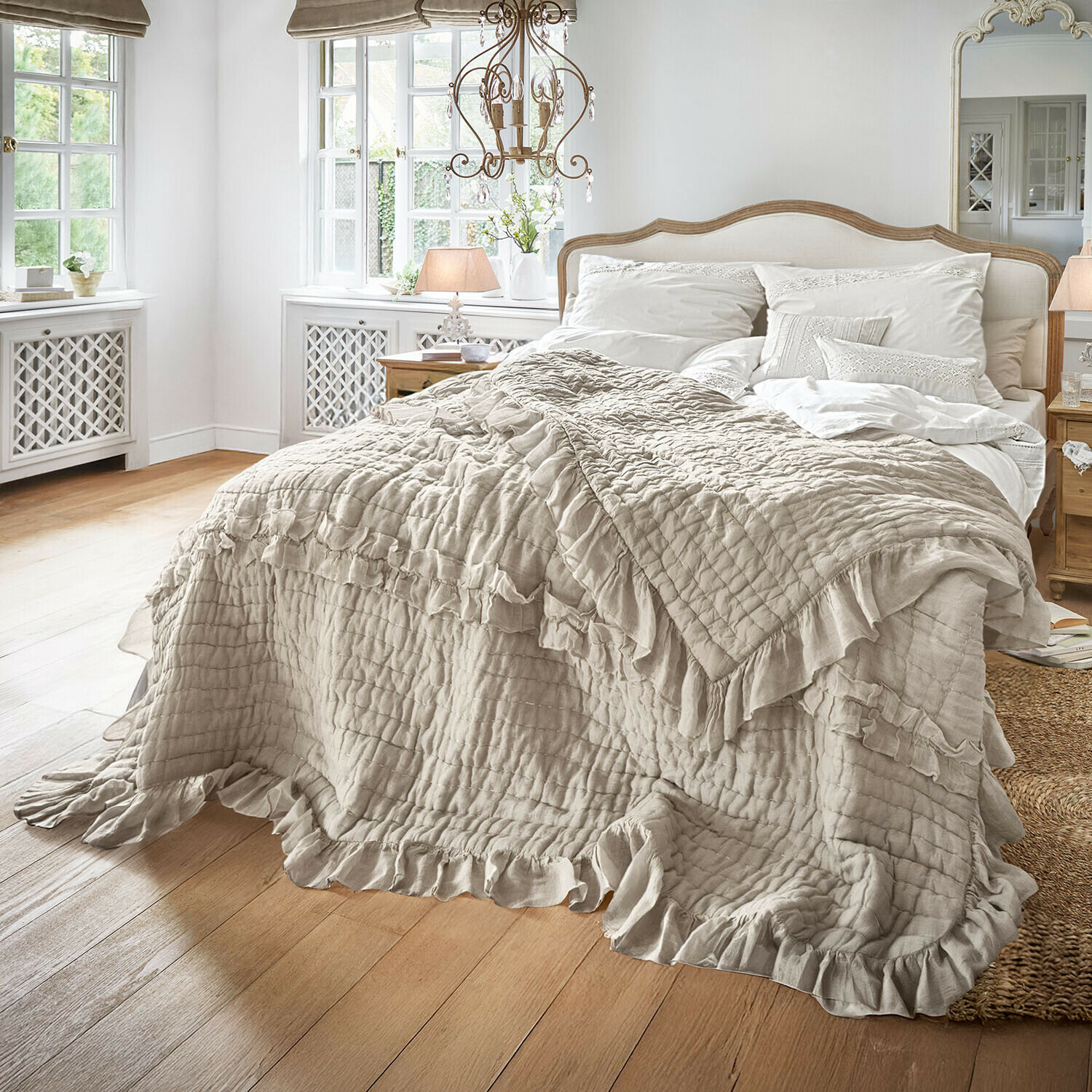Trapunta Calennent Copriletto beige con volant in tessuto morbido su letto in camera luminosa con pavimento in legno