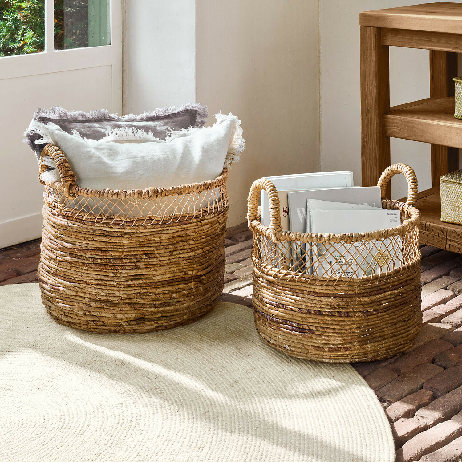 Due ceste in vimini naturale con manici, riempite di cuscini e libri per un'organizzazione decorativa