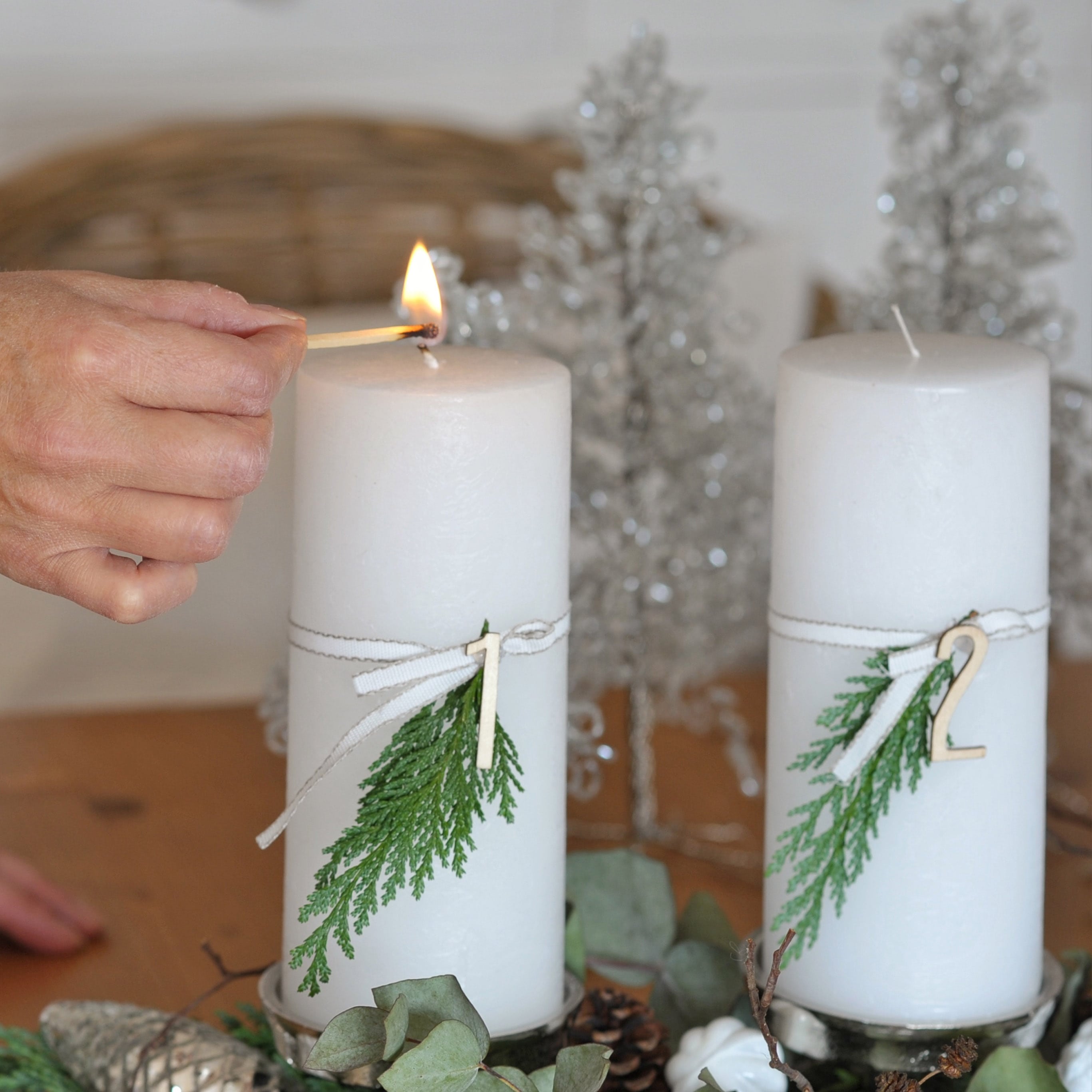 Candele bianche d'Avvento con rami verdi e numeri in legno su vassoio decorativo natalizio