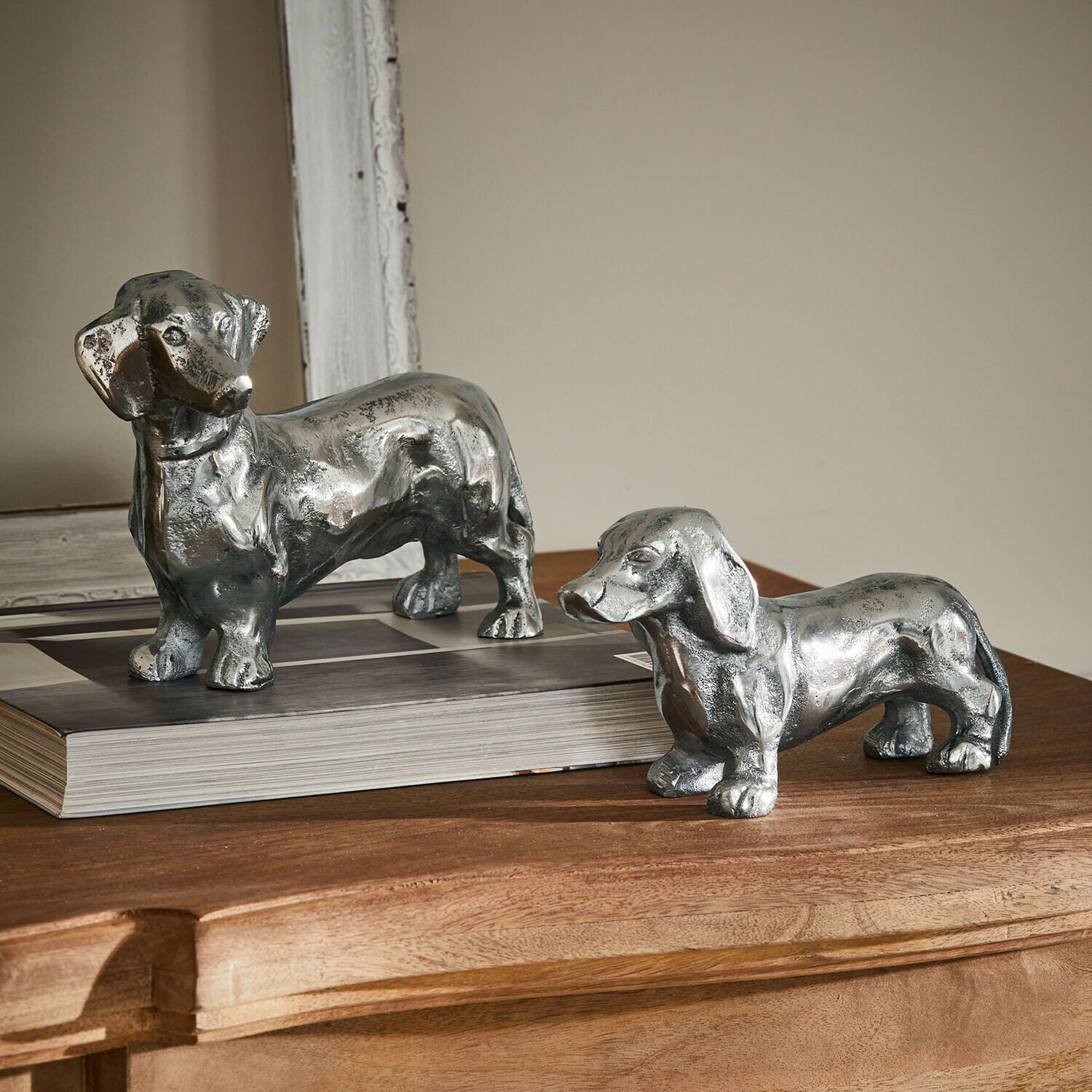 Set di 2 cani decorativi Calwen Due statuette di bassotti in metallo color argento su tavolo in legno, decorazione per interni
