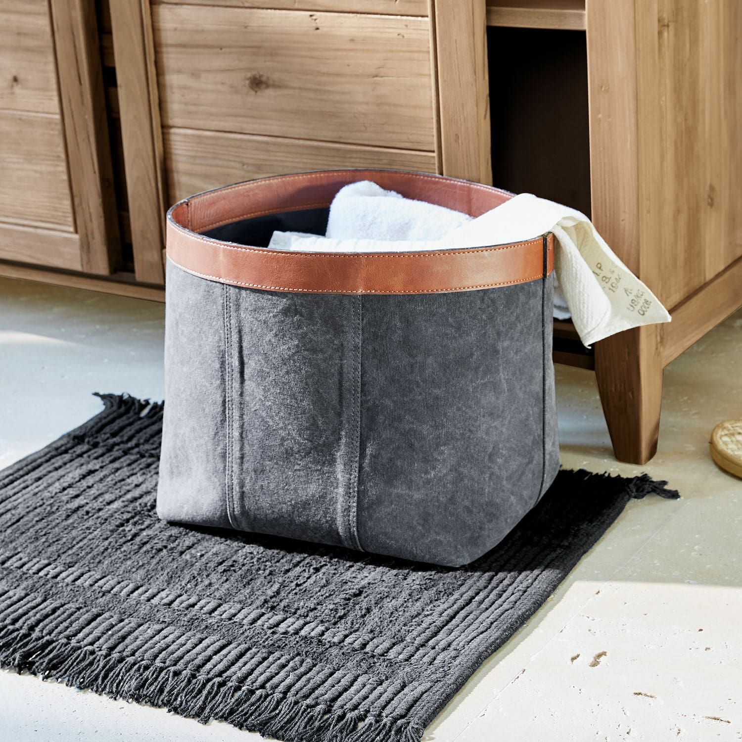 Cesto Chansonet Cesto grigio in tessuto con bordo in pelle marrone su tappeto nero per conservare tessuti