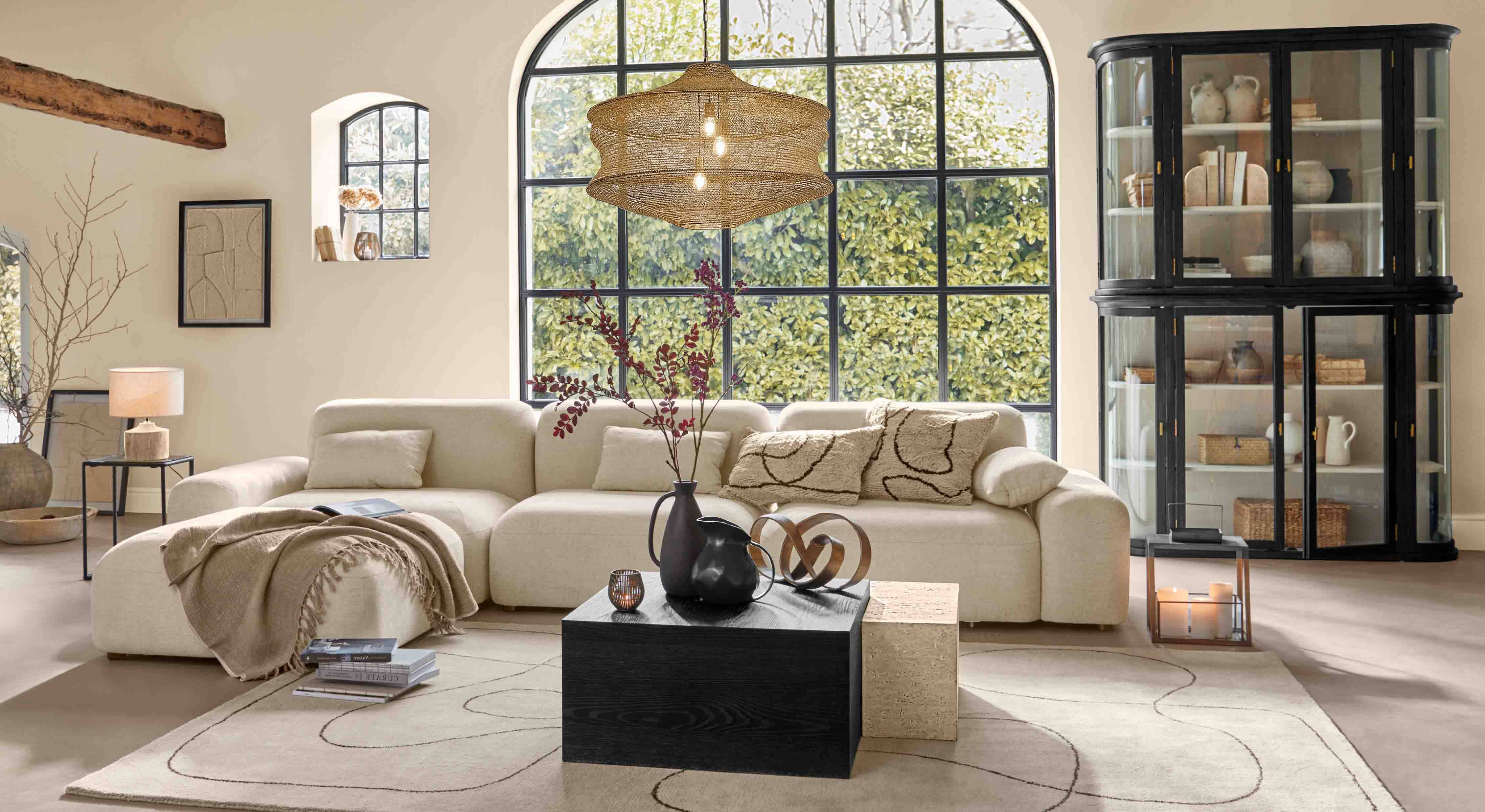 Soggiorno accogliente con divano beige, mobile nero e grande finestra, illuminazione moderna e decorazioni