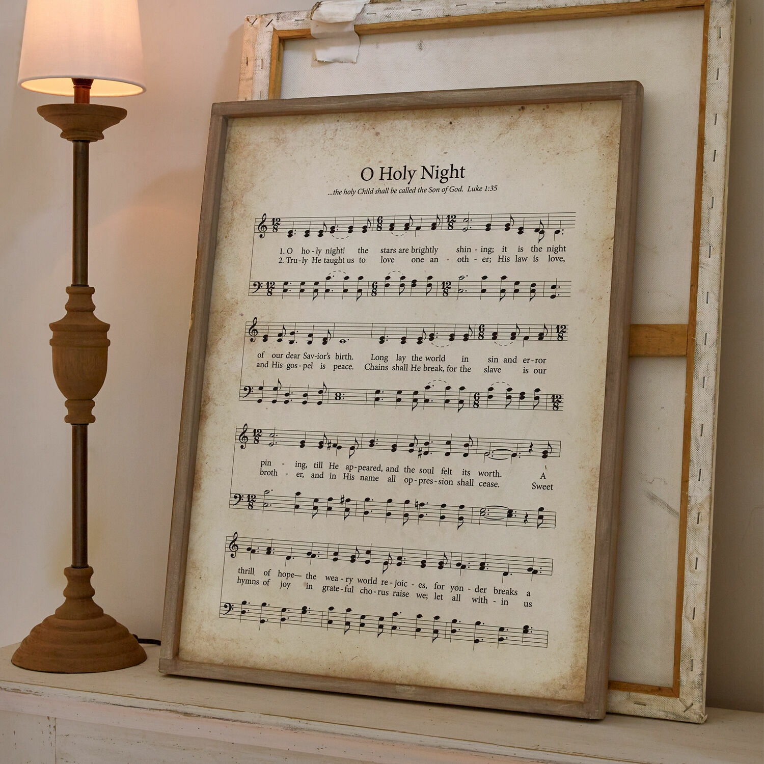 Quadro Holy Night Quadro con spartito e testo di O Holy Night in cornice di legno accanto a lampada