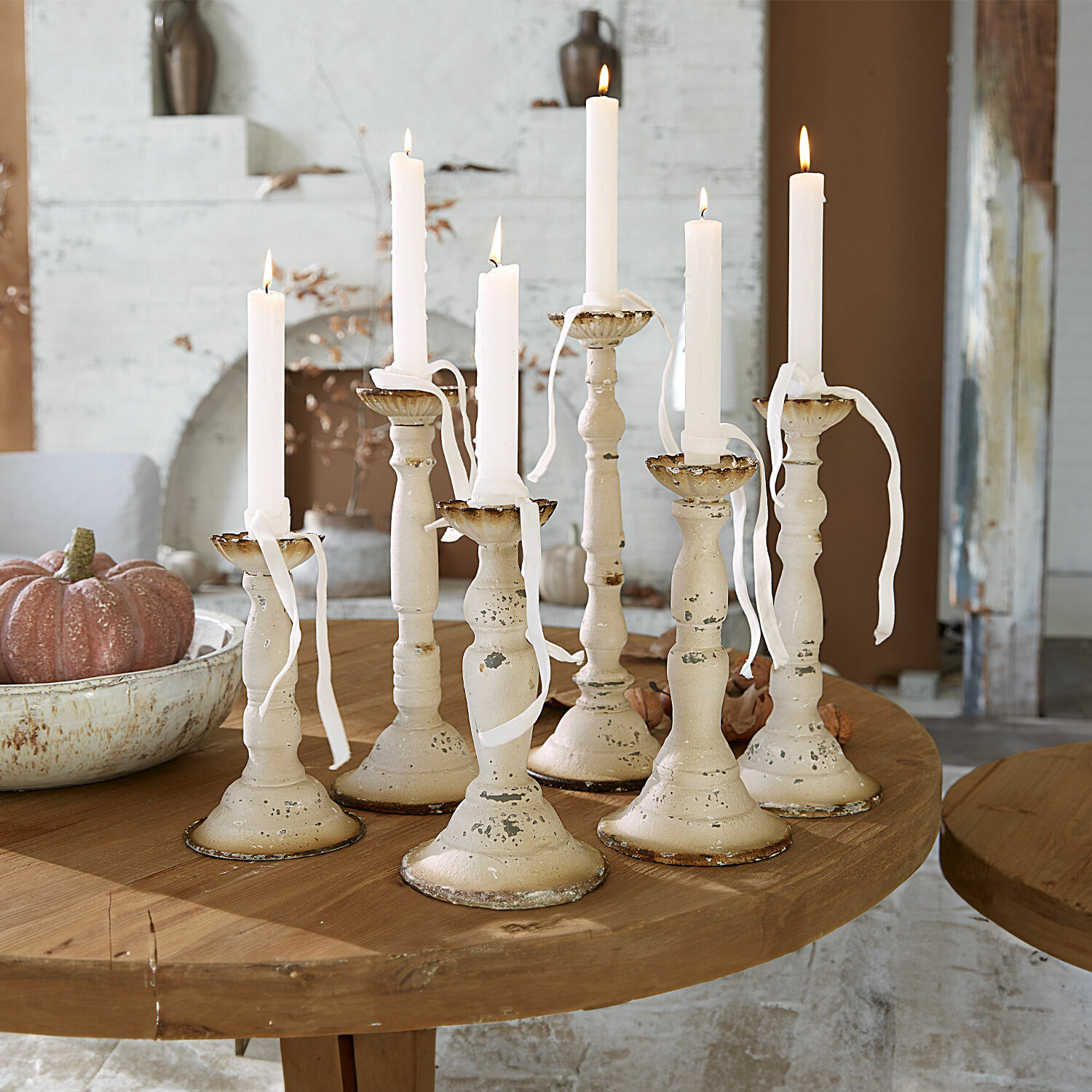 Set di 6 portacandele Rivondelle Set di sette candelabri in metallo crema con candele bianche su tavolo in legno, decorazione d'interni