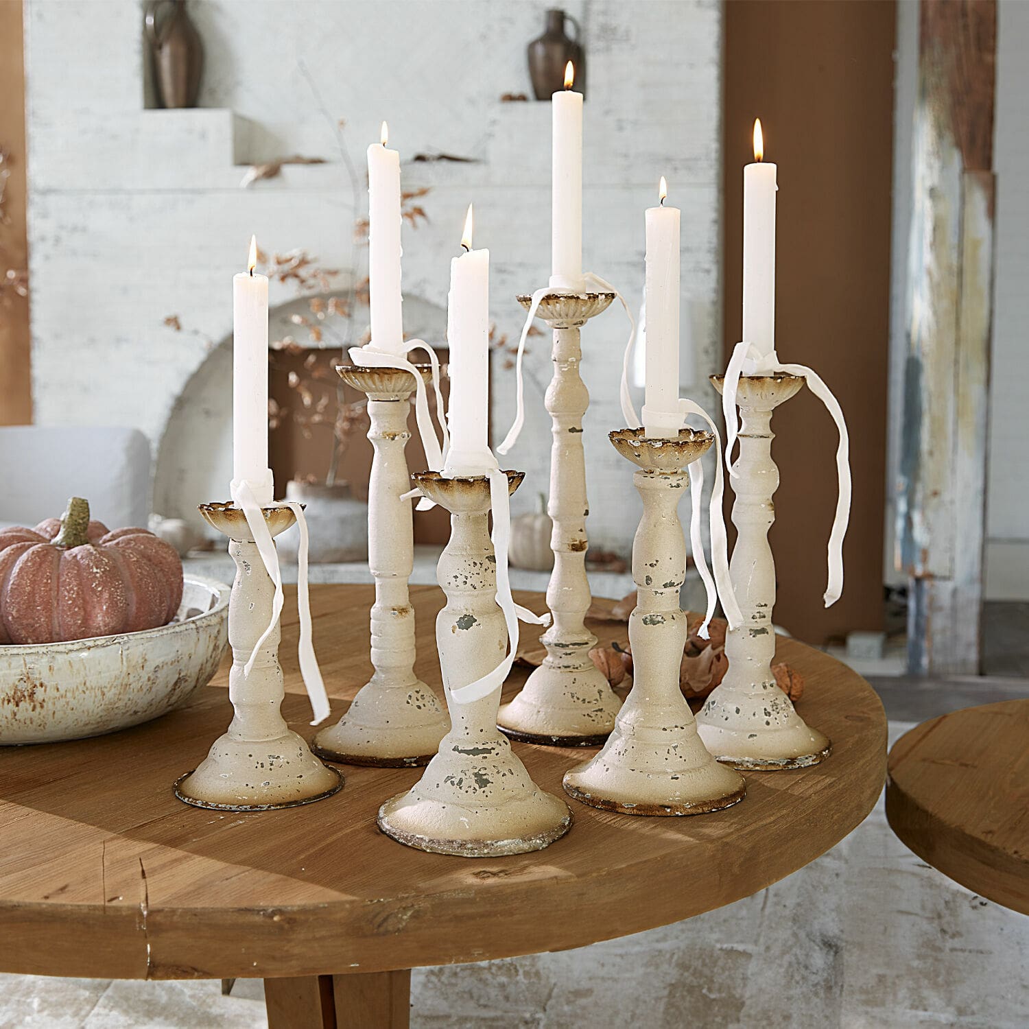 Set di 6 portacandele Rivondelle Set di sette candelabri in metallo crema con candele bianche su tavolo in legno, decorazione d'interni