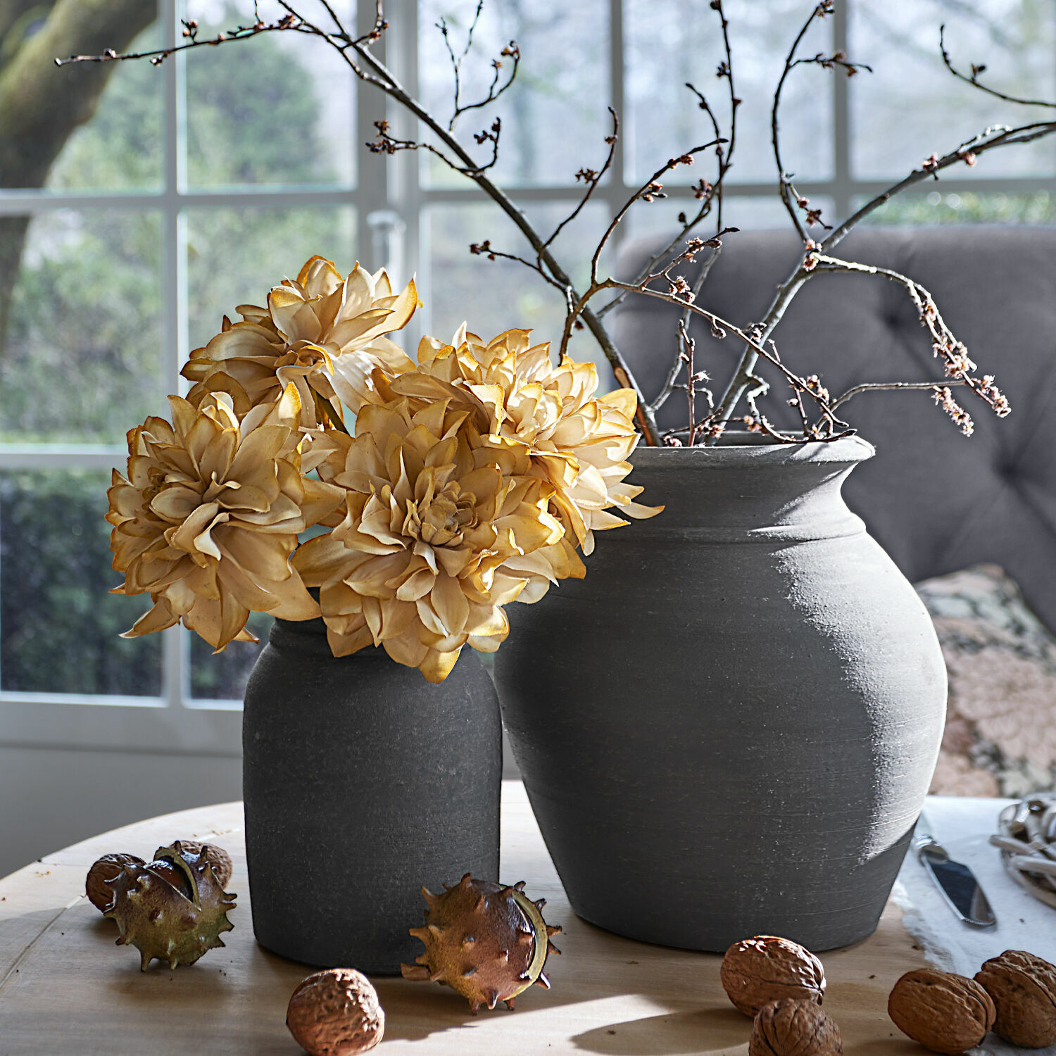Coppia di vasi Molduc Due vasi in ceramica grigia con fiori secchi e rami su tavolo in legno con noci