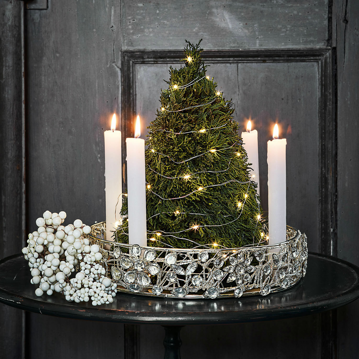 Portacandele Hope Decorazione natalizia con albero verde, candele bianche e corona decorativa argento su tavolo nero