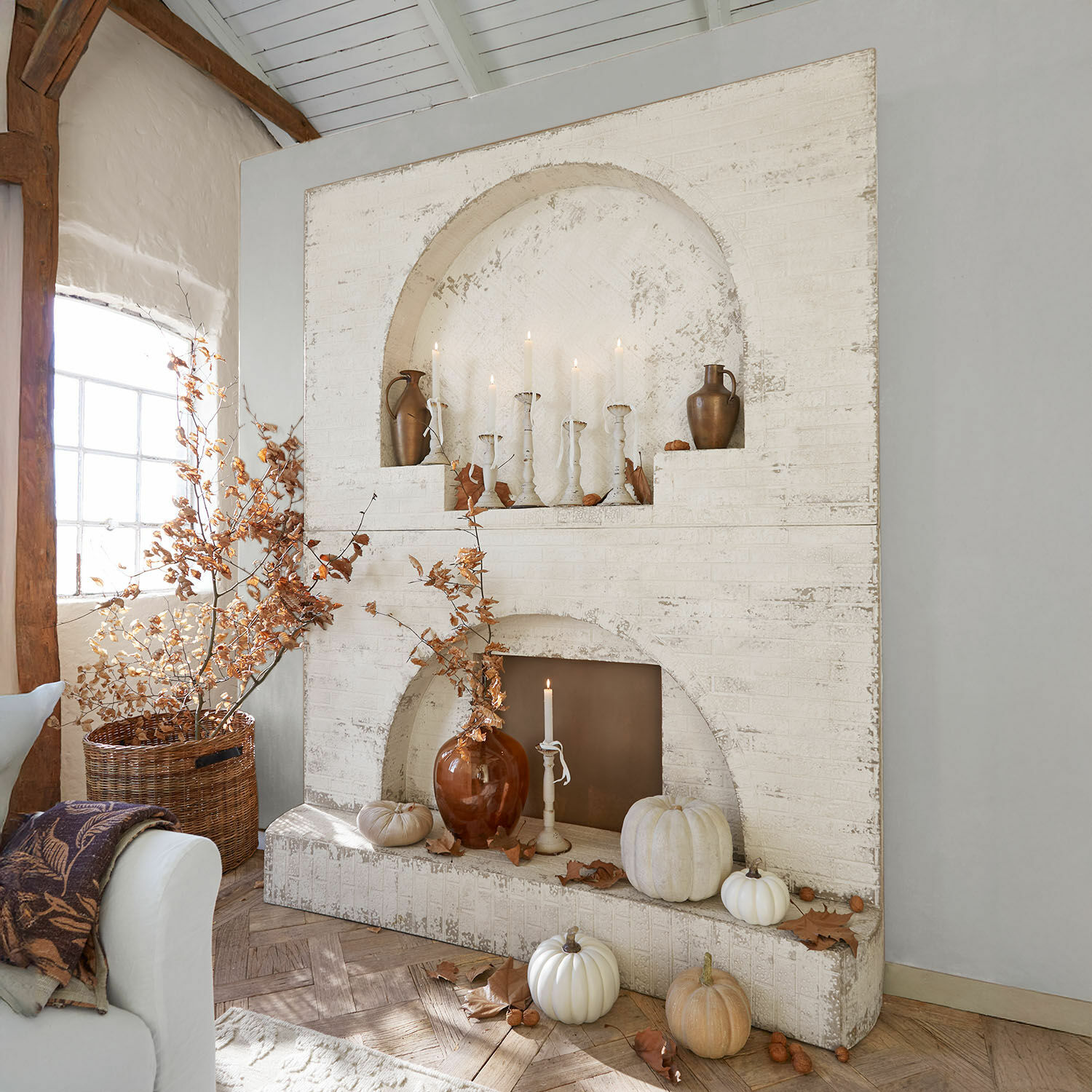 Consolle caminetto Forêt Émeraude Caminetto bianco in mattoni con decorazioni autunnali e candele in interno rustico