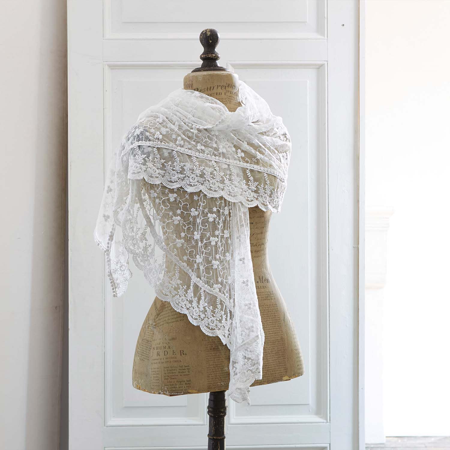 Sciarpa bianca in pizzo fine con motivo floreale su manichino, accessorio elegante per abbigliamento