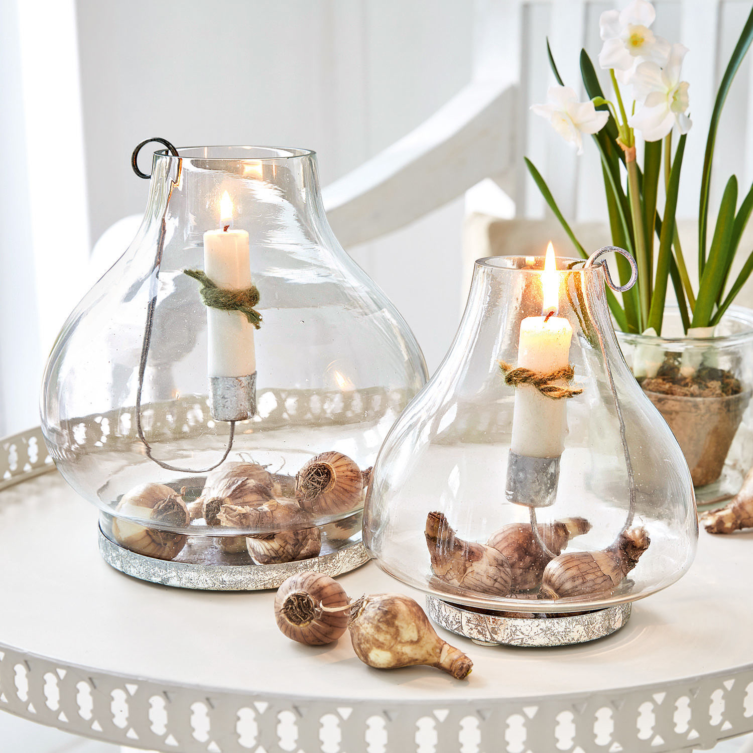 Coppia di portacandele Vallereuil Lanterna in vetro con candele bianche e bulbi di fiori su tavolo decorativo in metallo bianco