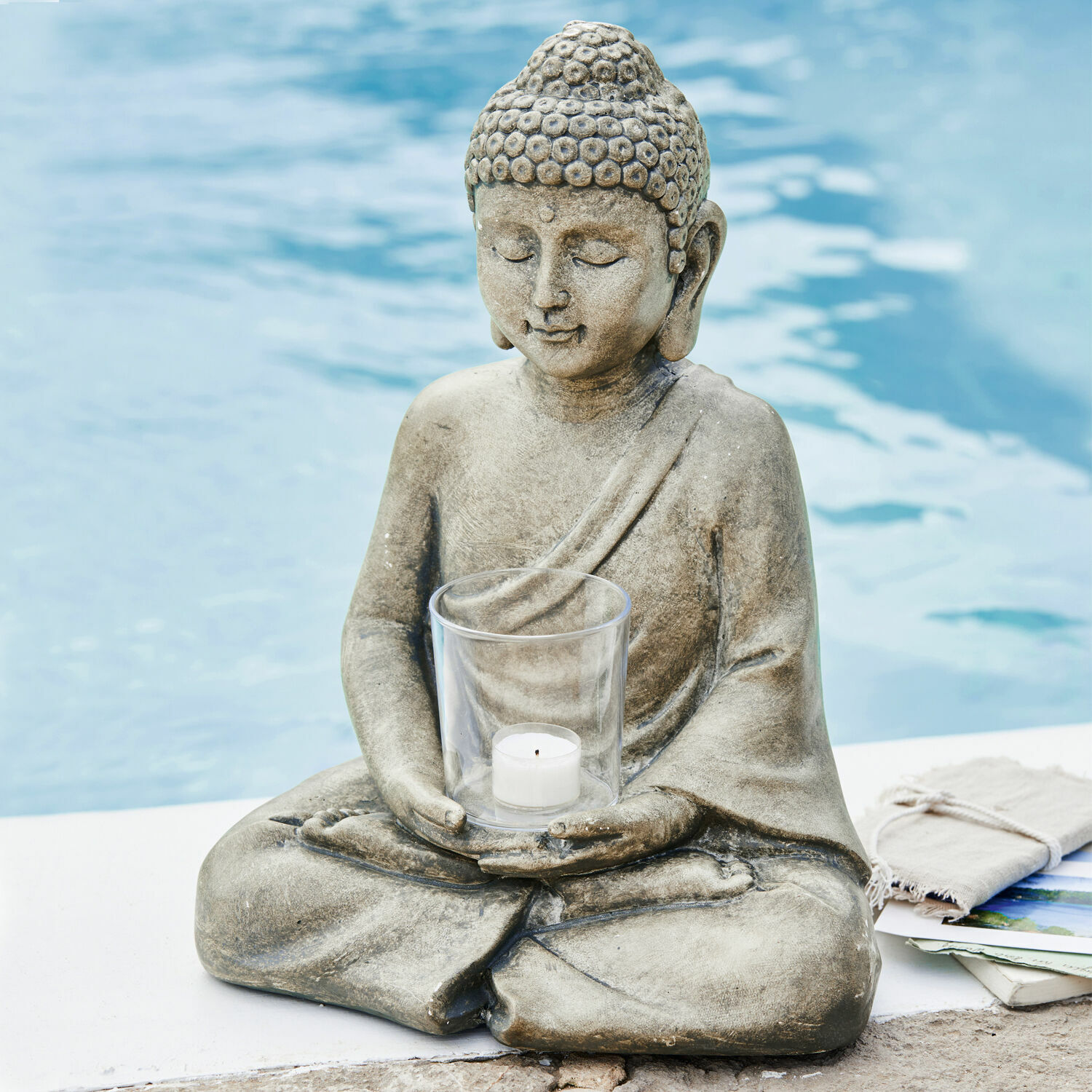 Portacandela Sylvain Statua di Buddha in pietra grigia con portacandela trasparente per tealight vicino alla piscina