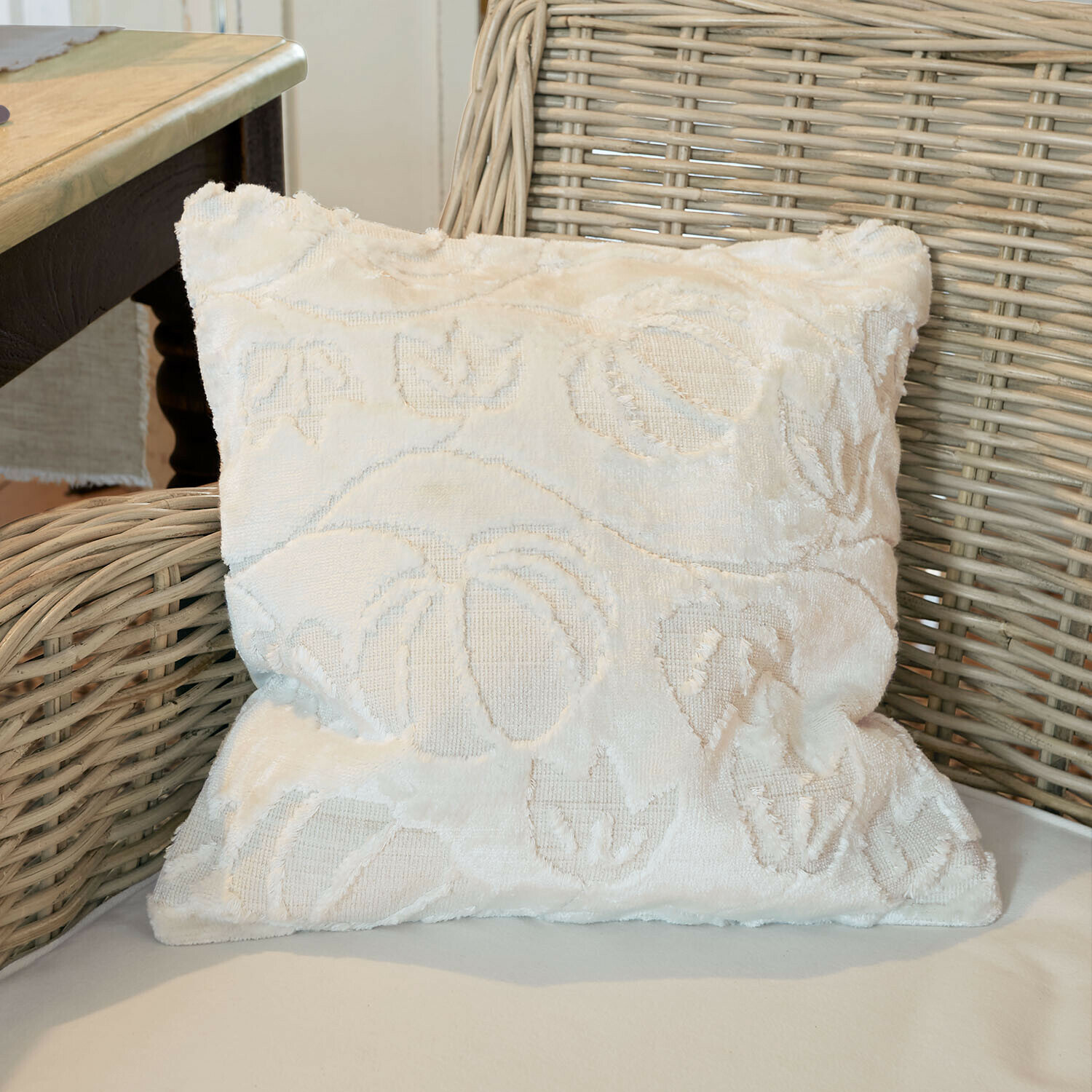 Copricuscino Élomiane Cuscino decorativo bianco in tessuto morbido con motivo floreale su poltrona in vimini