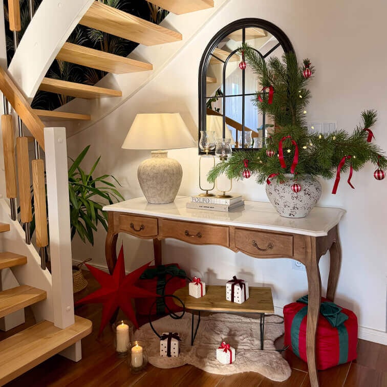 Tavolo in legno con piano in marmo, lampada e decorazione natalizia con rami verdi e ornamenti rossi