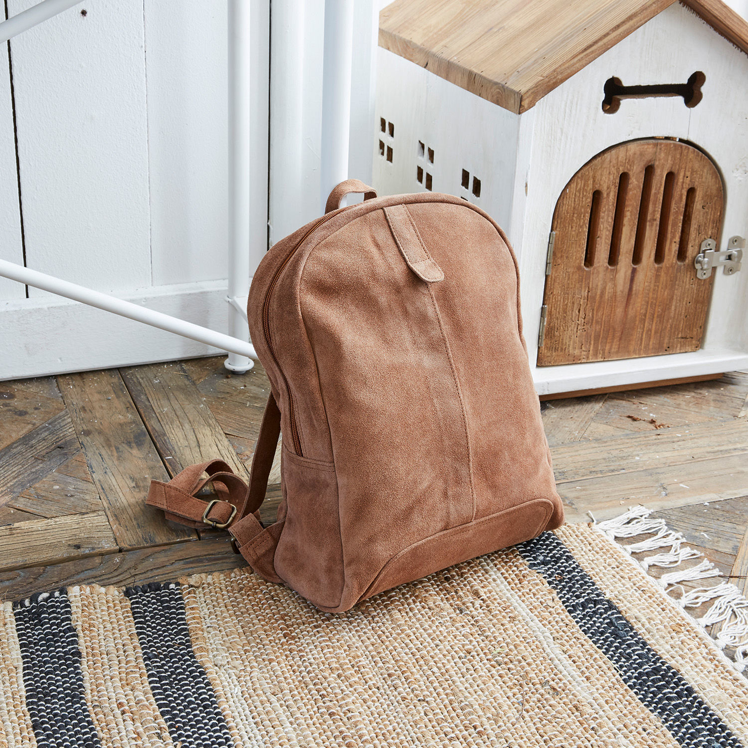 Zaino Palau Zaino in camoscio marrone su pavimento in legno accanto a casetta bianca per cani