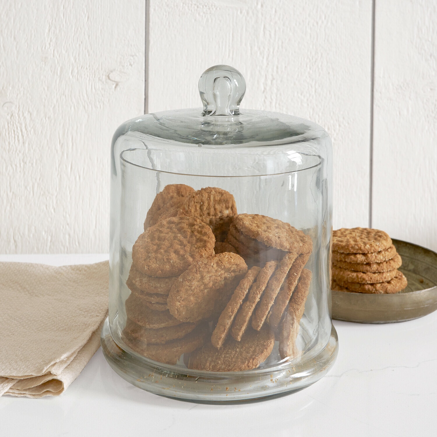 Vaso a campana in vetro Aislora Contenitore in vetro trasparente con coperchio pieno di saponi color crema su sfondo bianco
