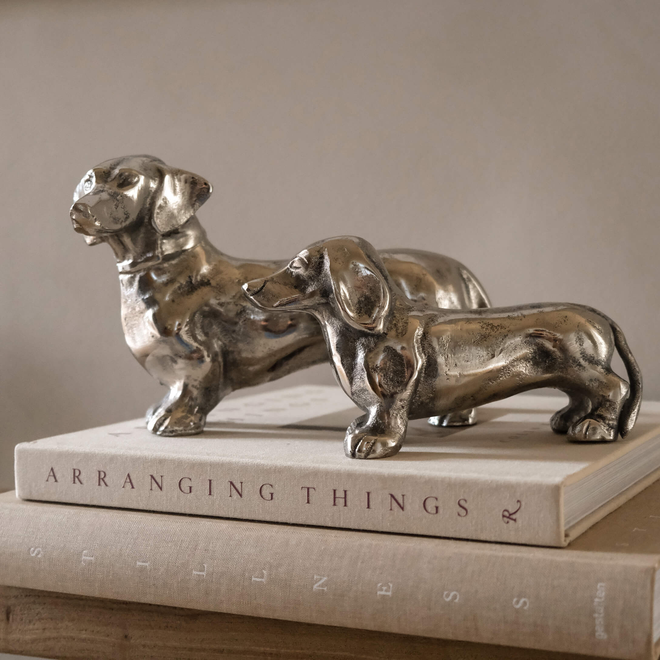 Due statuette di bassotti in metallo color argento su libri, decorazione per interni