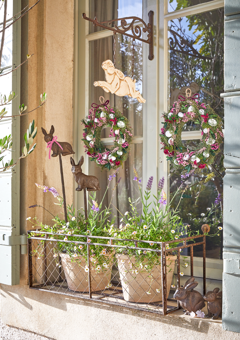 Decorazione per finestra con supporto in metallo, vasi con fiori e corone primaverili con uova e conigli