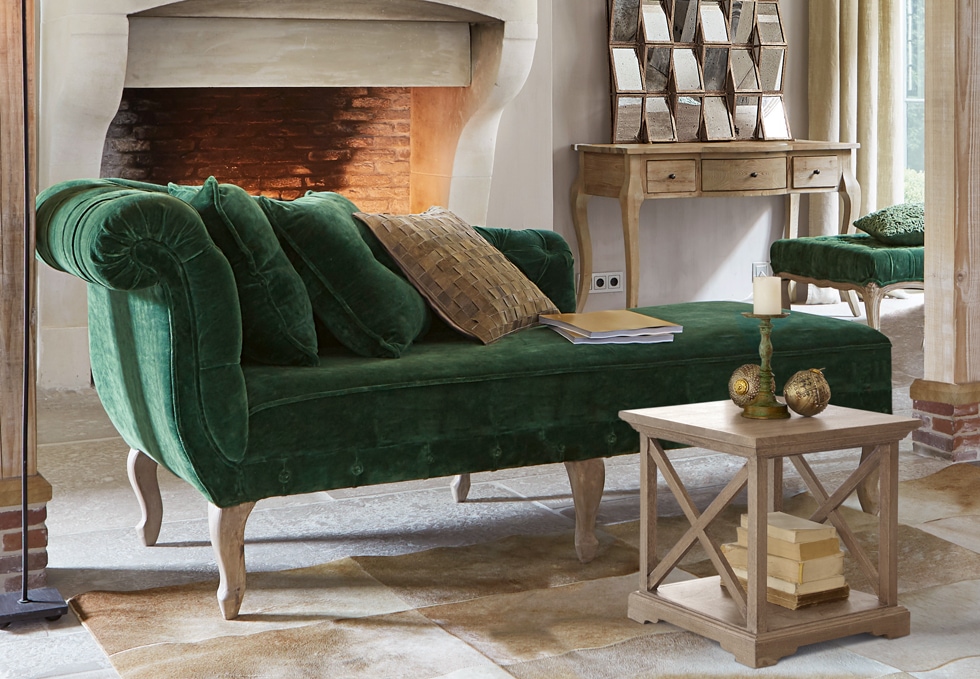 Divano classico verde in velluto con gambe in legno in soggiorno elegante con camino