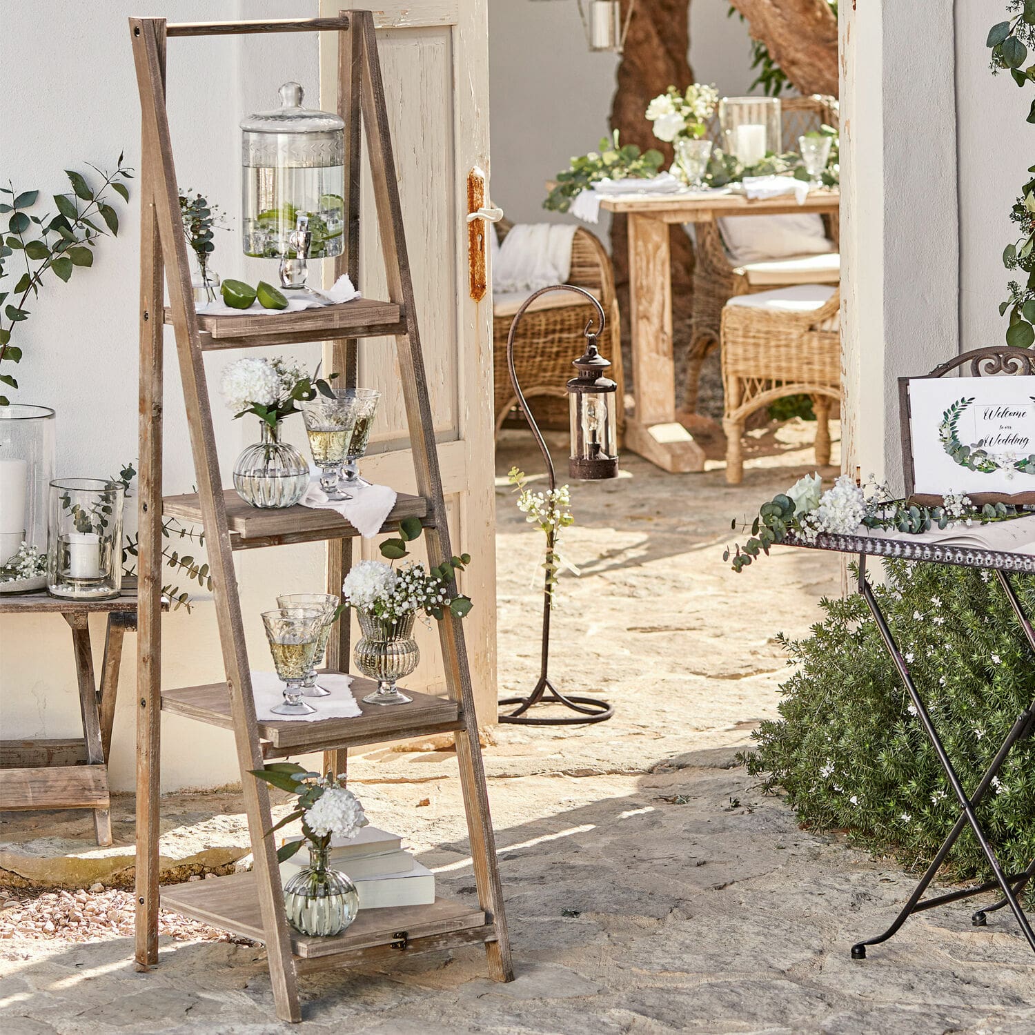 Scaffale Lester Scala in legno con ripiani decorati da vasi di vetro su patio in pietra in stile rustico