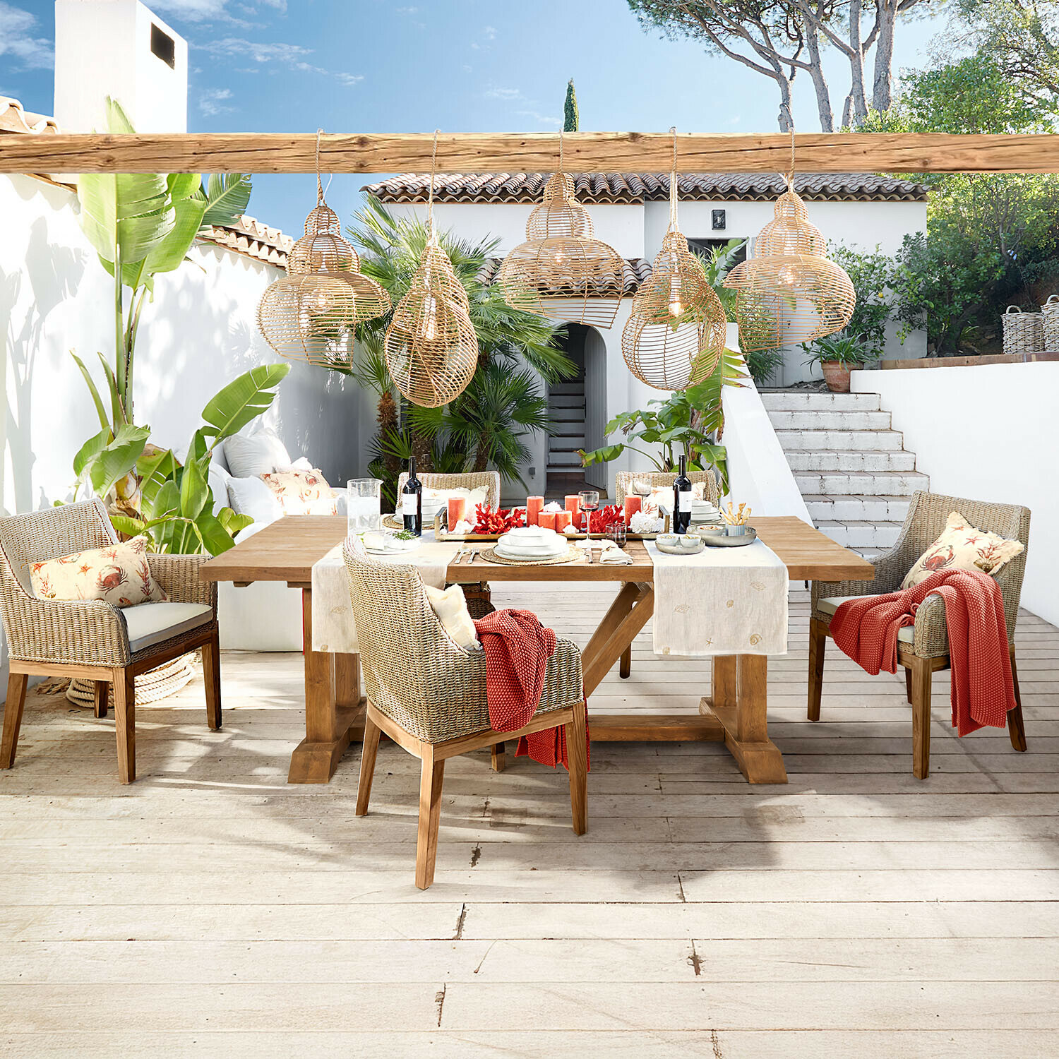 Set di mobili da giardino in legno e rattan naturale con lampade a sospensione in vimini su terrazza