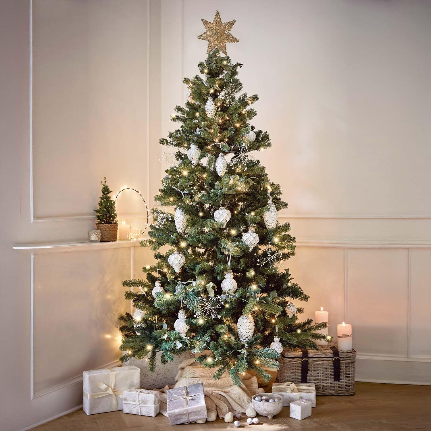 Albero di Natale decorato con palline bianche e luci, regali e candele in un ambiente accogliente
