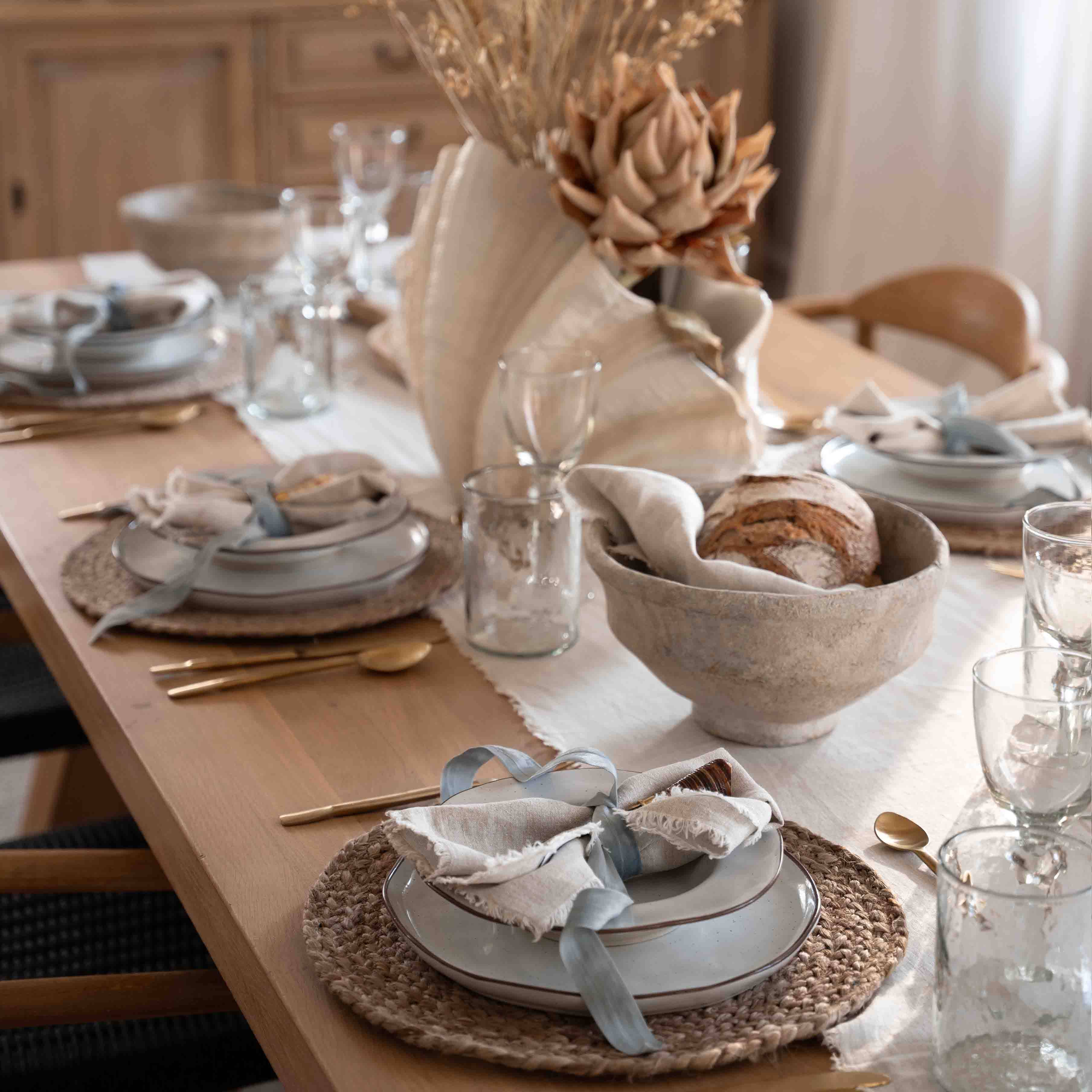 Decorazione da tavola con conchiglia naturale e pane in ciotola di lino su tavolo in legno
