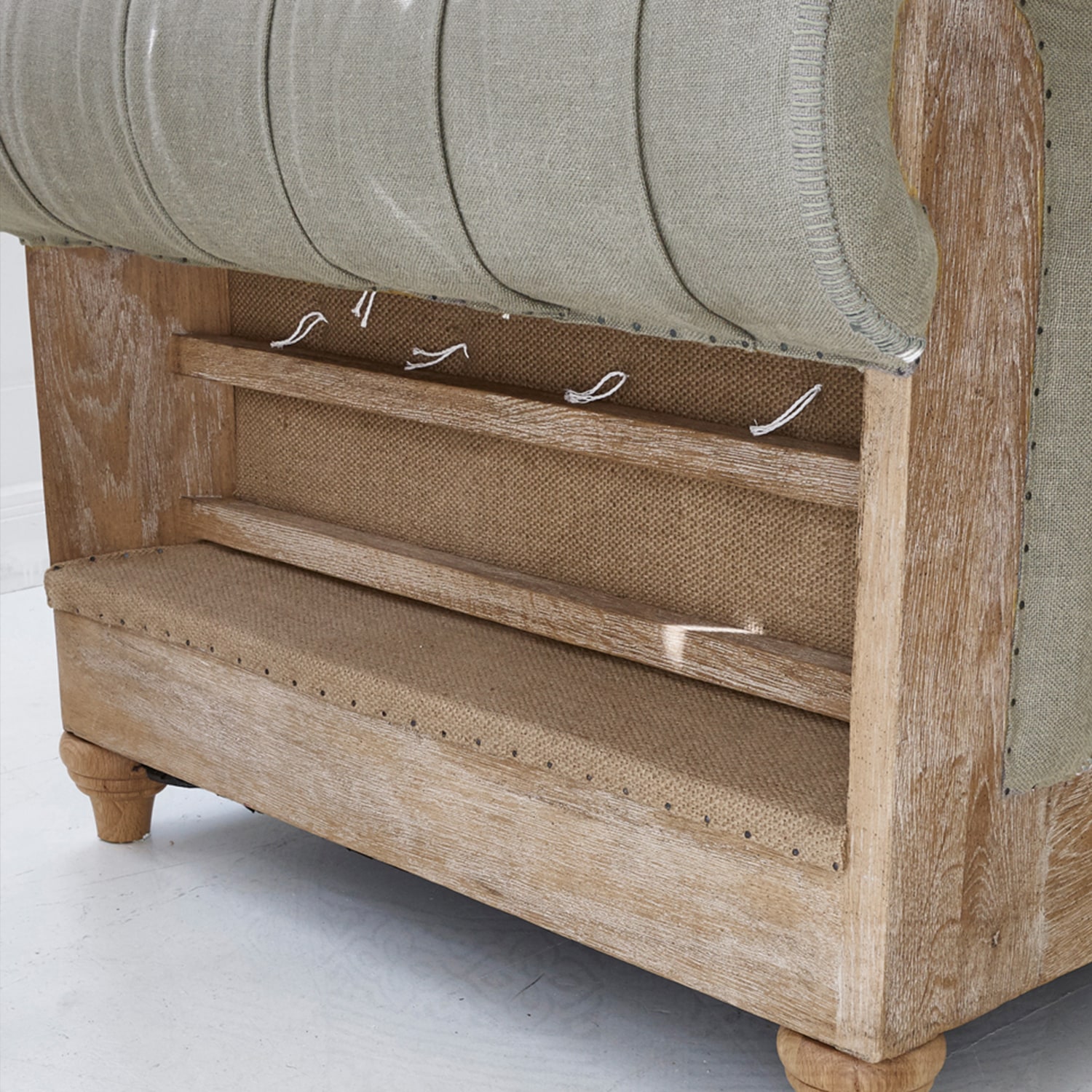 Divano in legno chiaro e tessuto beige con struttura visibile e dettagli di finitura