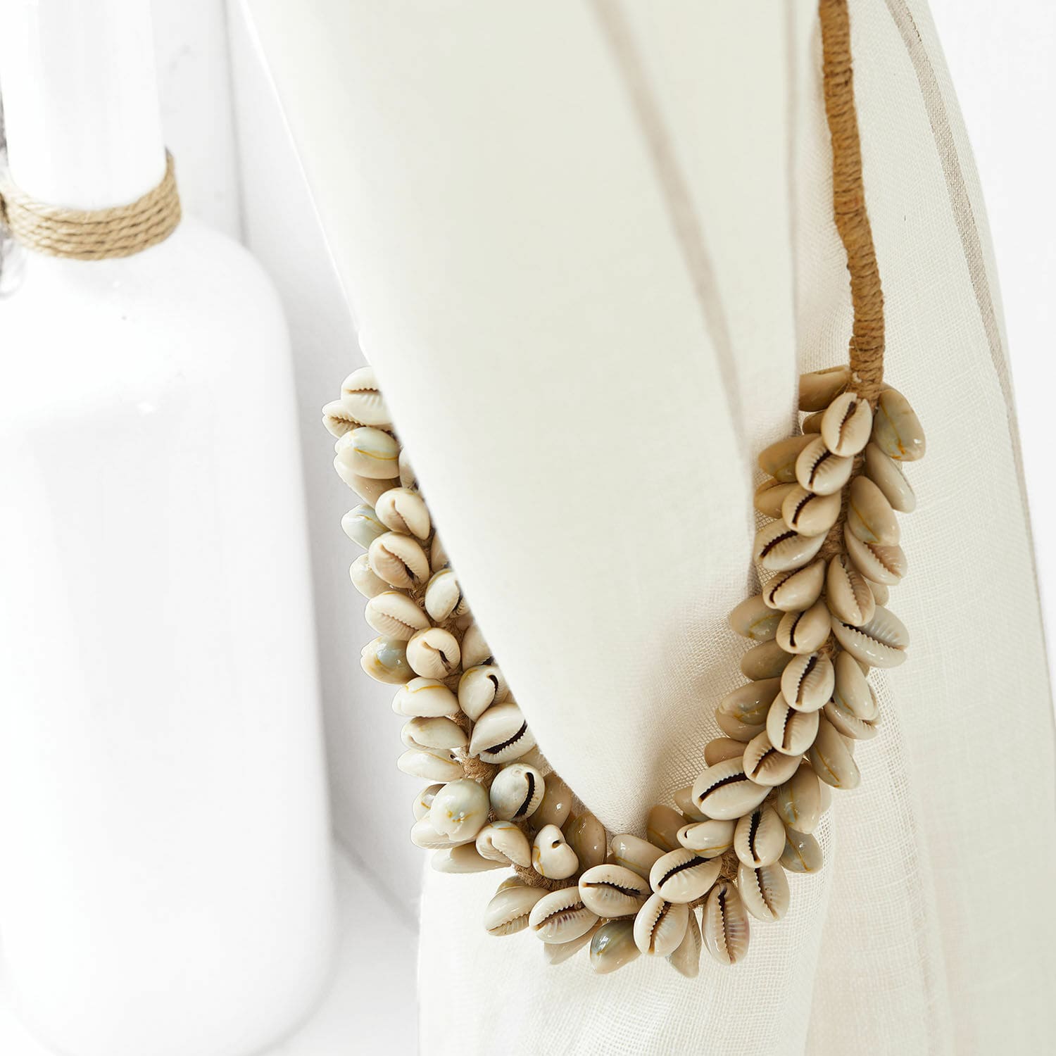 Fermatenda Alix Corona decorativa di conchiglie naturali beige su tessuto di lino