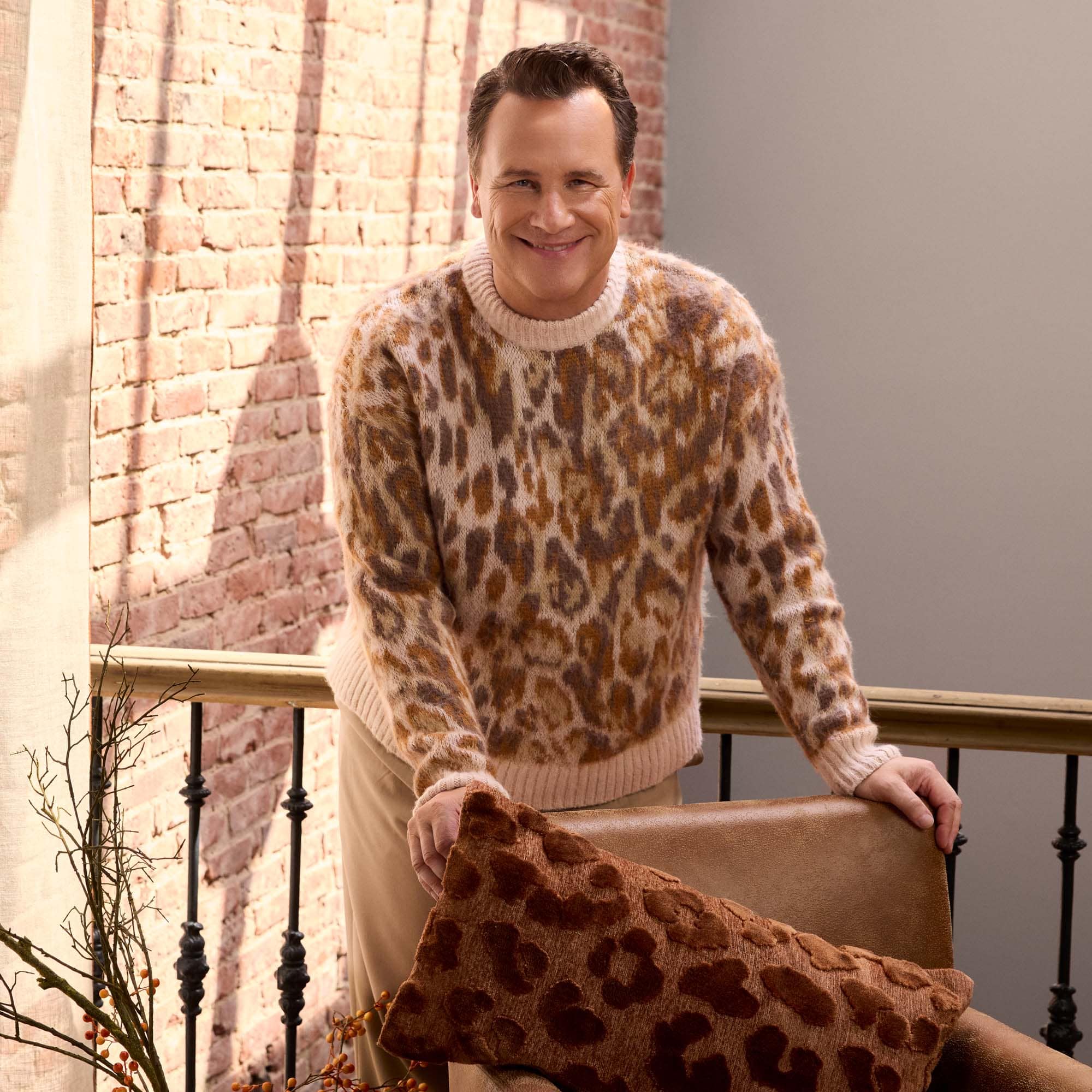 Uomo con maglione morbido a motivo leopardato marrone chiaro vicino a muro di mattoni