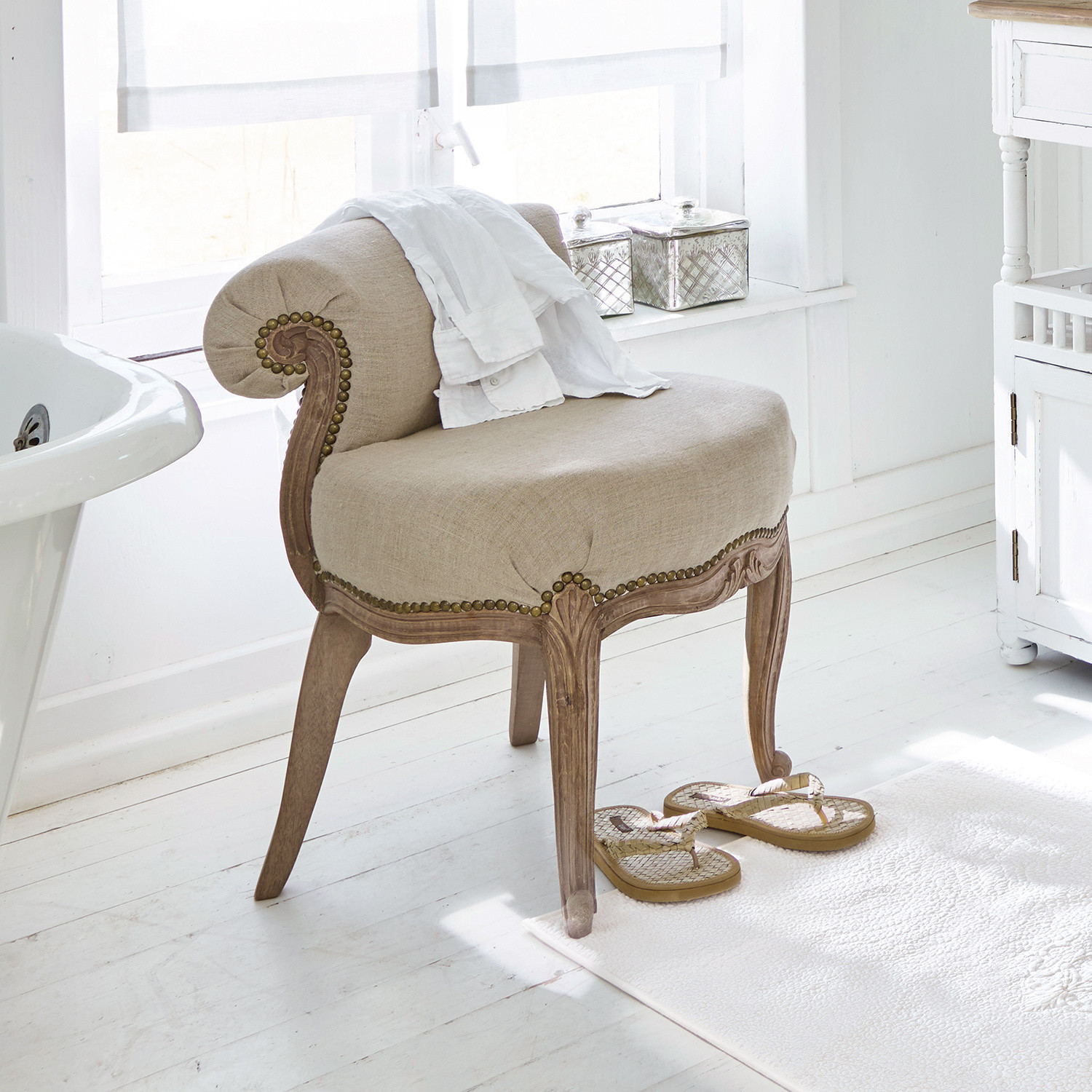Poltrona Rivel Poltrona beige imbottita con cornice in legno intagliato in bagno luminoso