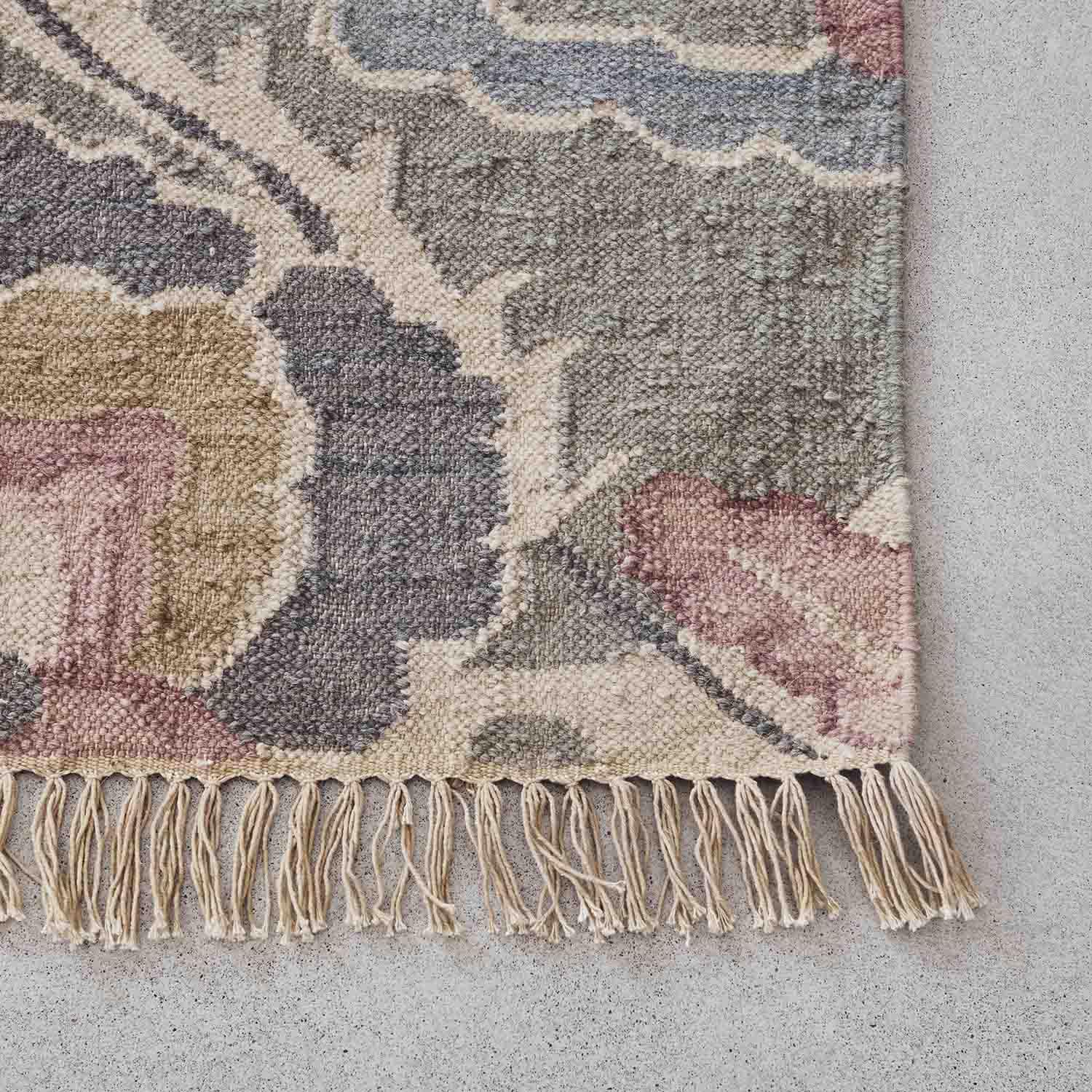 Tappeto con frange in tonalità pastello rosa, grigio e beige, materiale morbido con motivo decorativo
