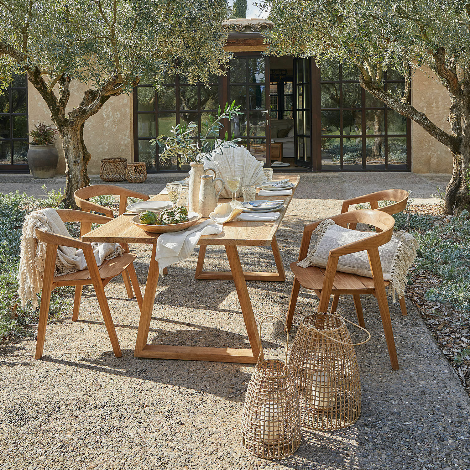 Tavolo Saulny Set di mobili da giardino in teak naturale con decorazioni e lanterne su terrazza soleggiata