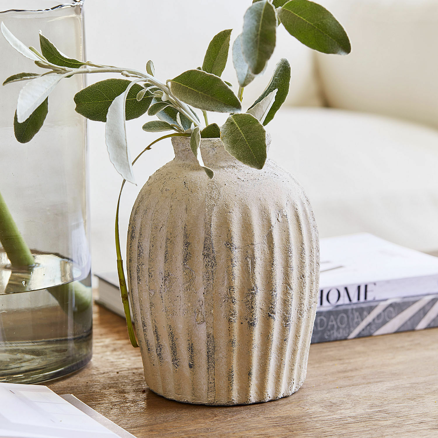 Vaso Melissa Vaso in ceramica beige con texture e foglie verdi su tavolo in legno per decorazione d'interni