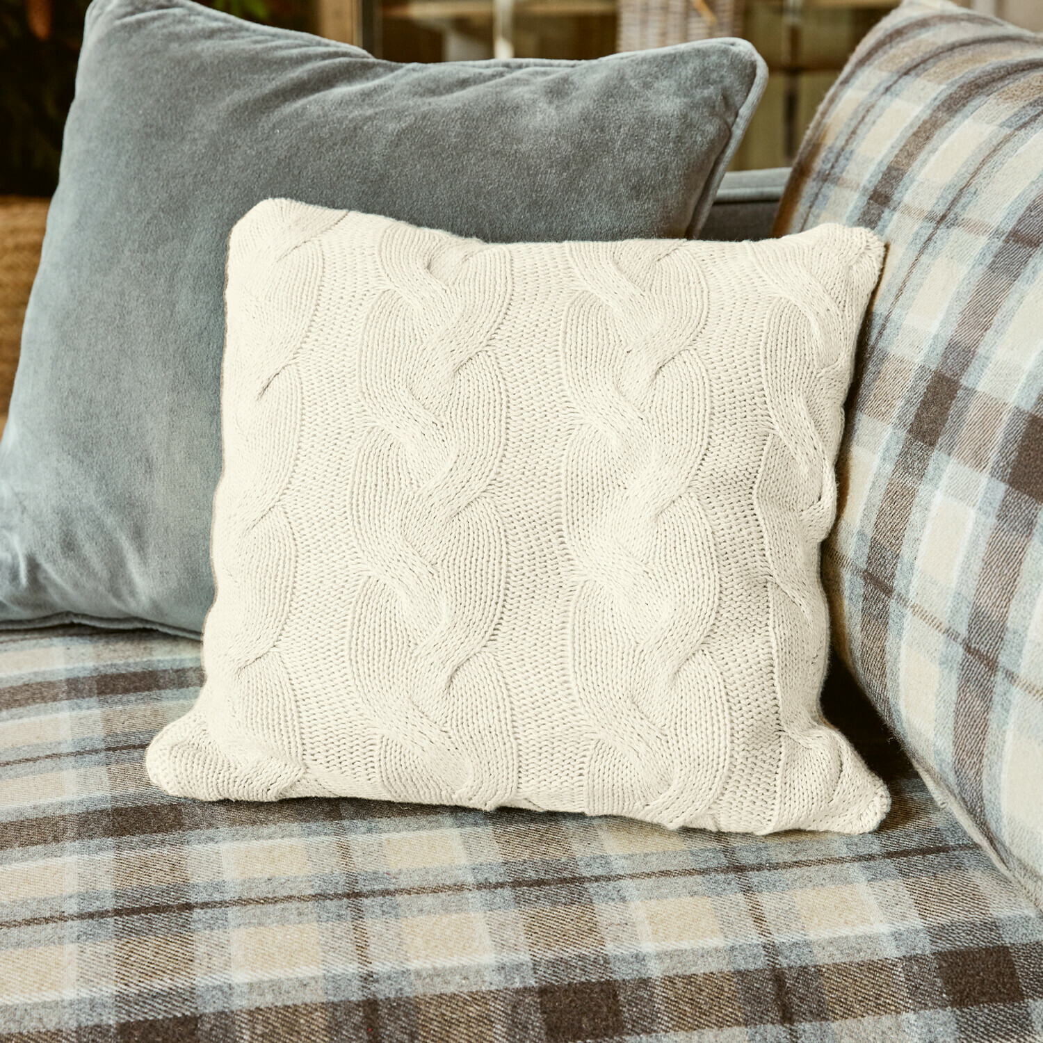Copricuscino Arnhem Cuscino beige lavorato a maglia con motivo a treccia su divano a quadri, decorazione accogliente