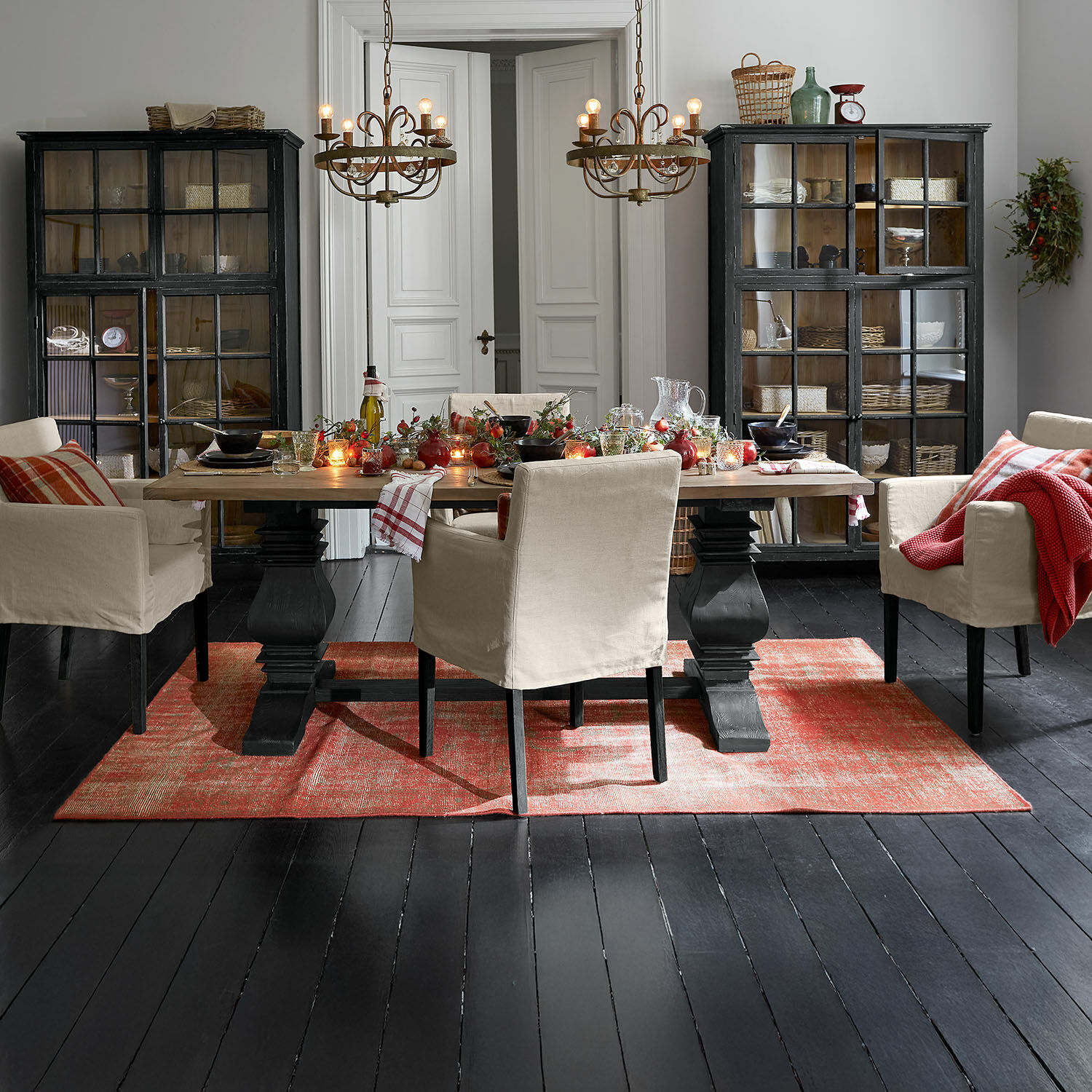 Tappeto Yalora Sala da pranzo con tavolo in legno, sedie beige e tappeto rosso su pavimento nero, decorazioni festive