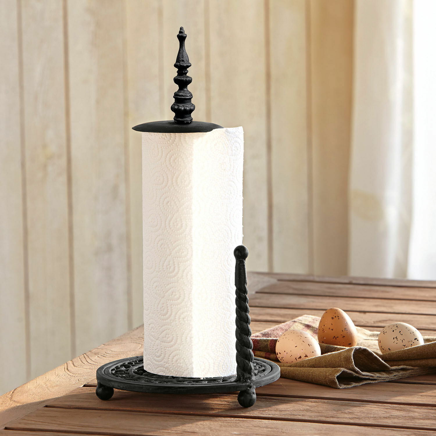 Portarotolo Dudley Porta rotolo in metallo nero su tavolo in legno con uova decorative accanto