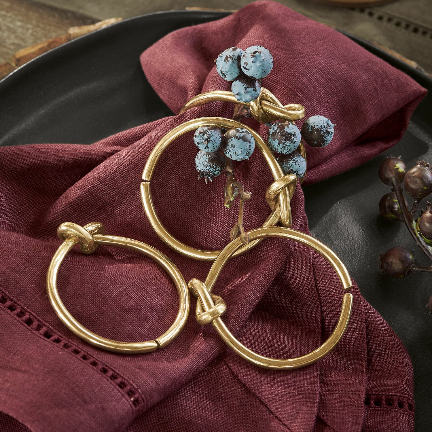 Set di 4 portatovaglioli ad anello Motje Set di tre anelli metallici dorati su tessuto di lino bordeaux con bacche decorative