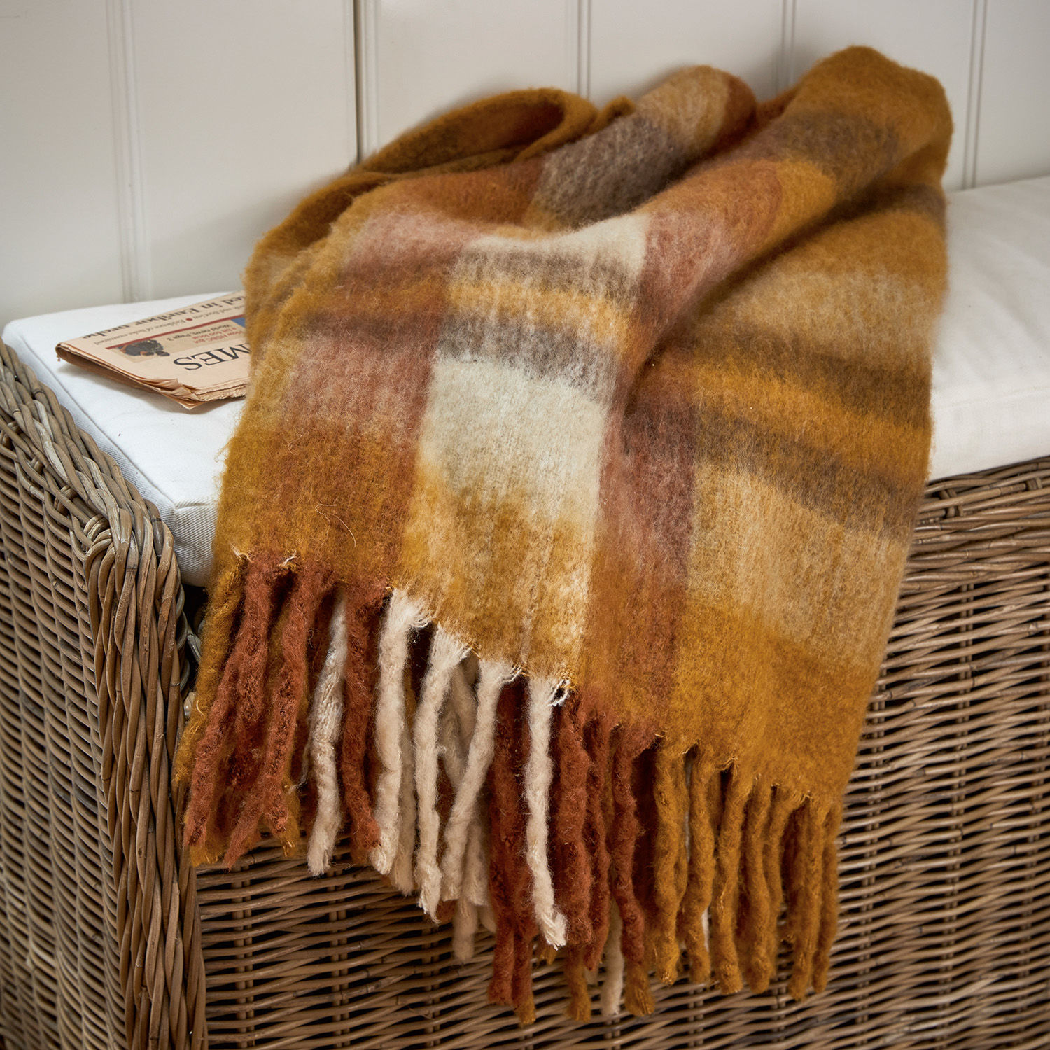 Plaid Alborg Coperta in lana morbida con tonalità calde marroni e beige con frange su poltrona in vimini