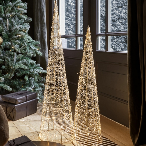 Due decorazioni coniche in filo dorato con luci LED calde vicino a una finestra.