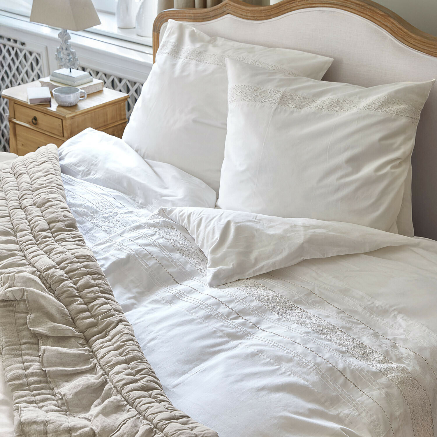 Biancheria da letto Isolineas Biancheria da letto bianca con pizzo su letto in legno chiaro e coperta beige
