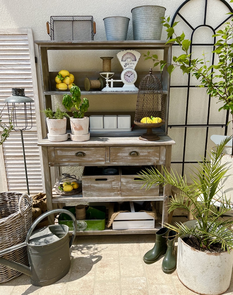 Mobile rustico in legno con scaffali e cassetti in stile vintage, decorazioni da giardino su terrazza soleggiata