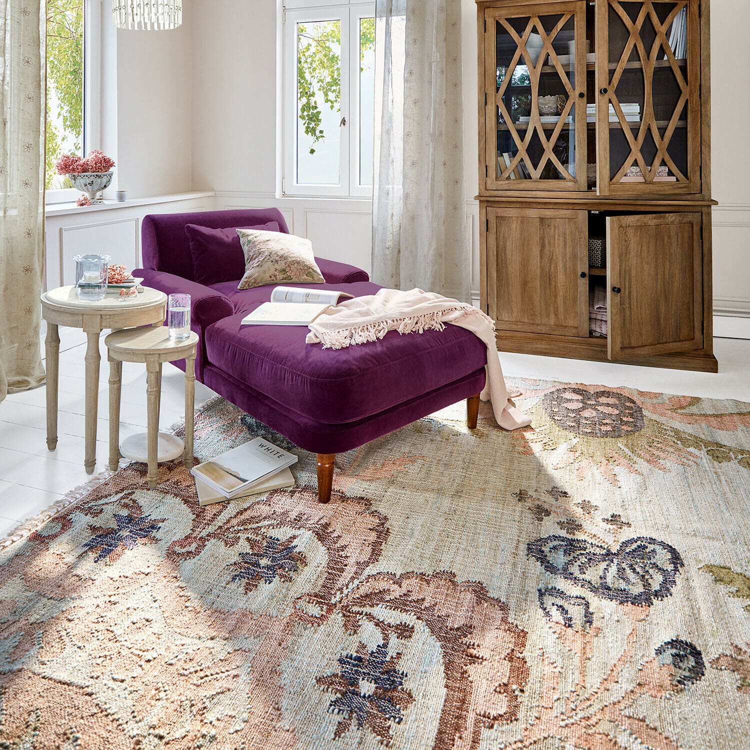 Tappeto Amélorie Chaise longue in velluto viola in soggiorno luminoso con mobile in legno e tappeto decorativo