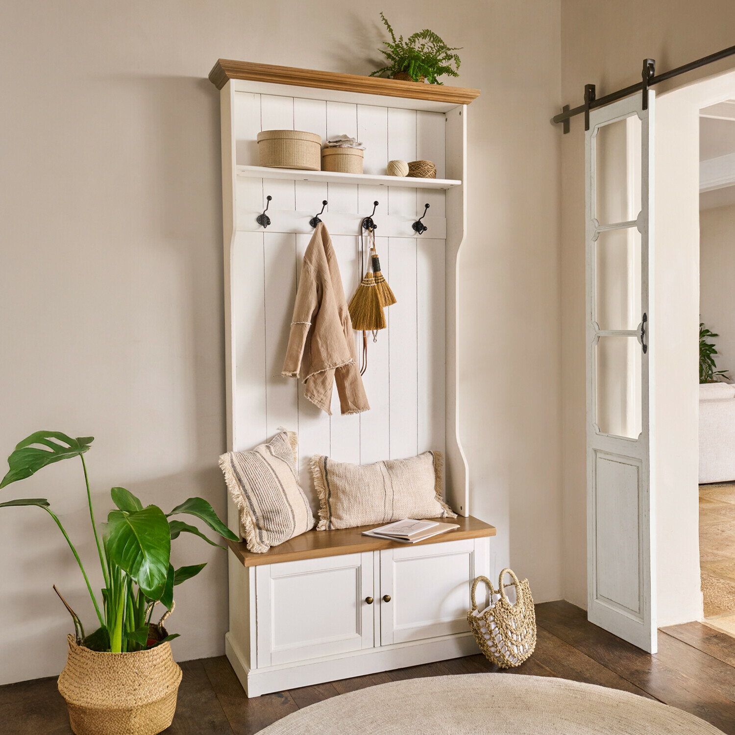 Mobile per ingresso Colchester Mobile ingresso bianco in legno con seduta, ganci, cuscini beige e decorazioni naturali con pianta verde