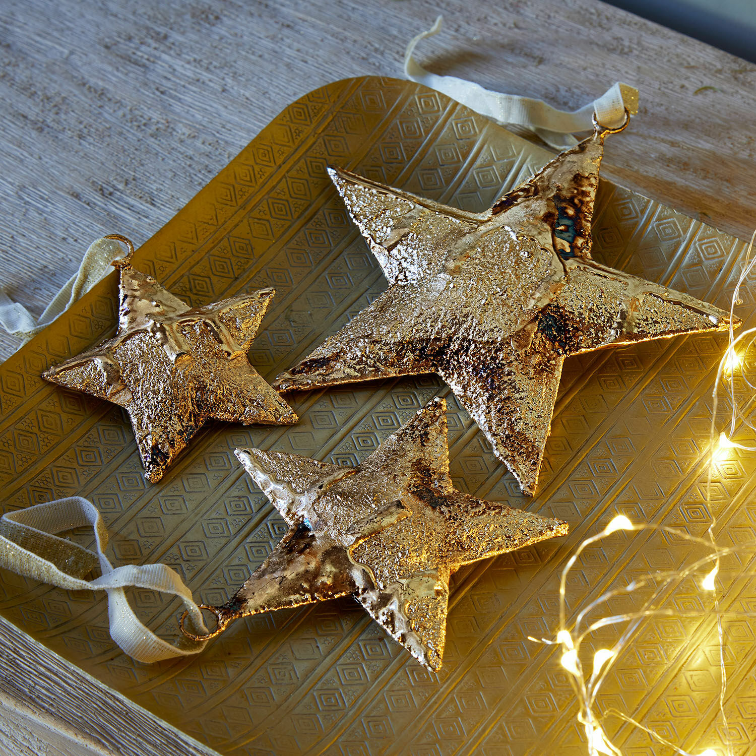 Set di 3 ciondoli Myrska Set di tre stelle decorative in metallo dorato su vassoio dorato con luci LED