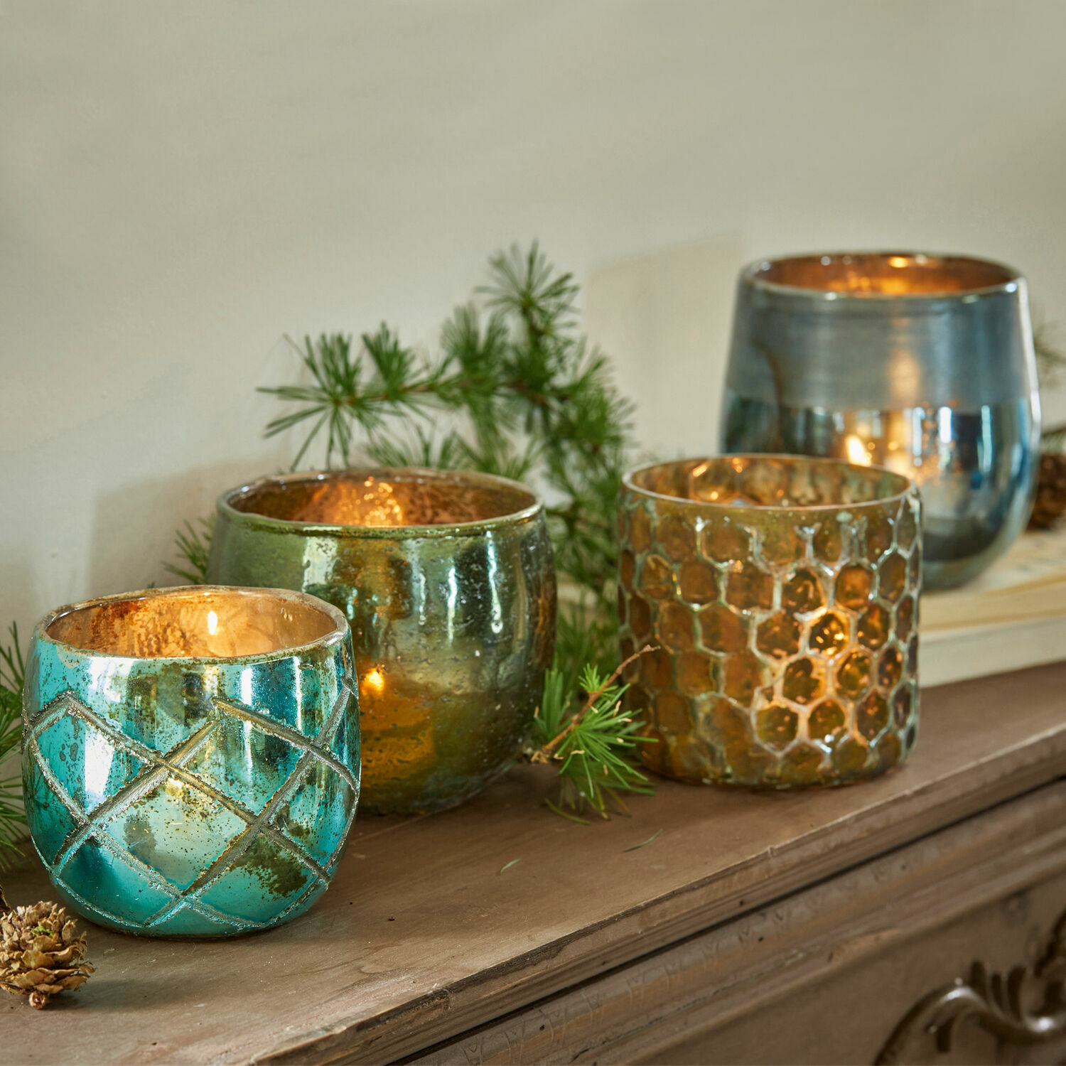 Set di 4 portalumini Marine Set di quattro portacandele in vetro turchese, verde e oro su una superficie in legno