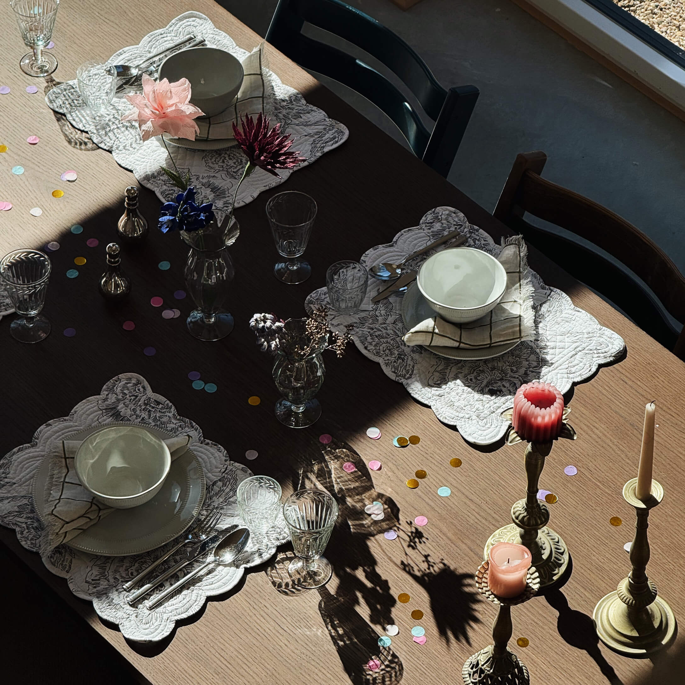 Tavolo in legno con ciotole in ceramica bianca, bicchieri e candele su candelabri in ottone
