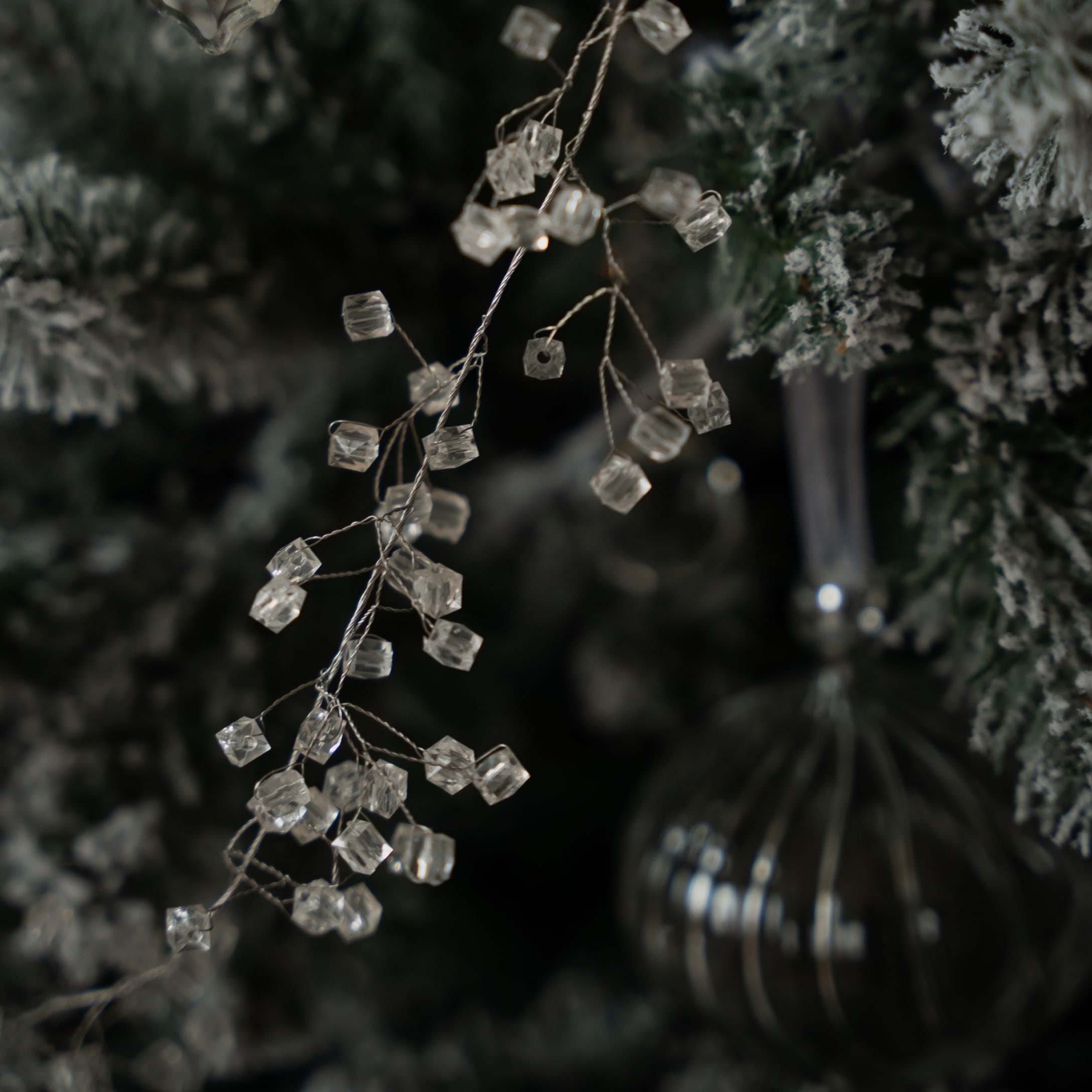 Decorazione natalizia con cristalli trasparenti su sfondo di albero artificiale verde con effetto neve